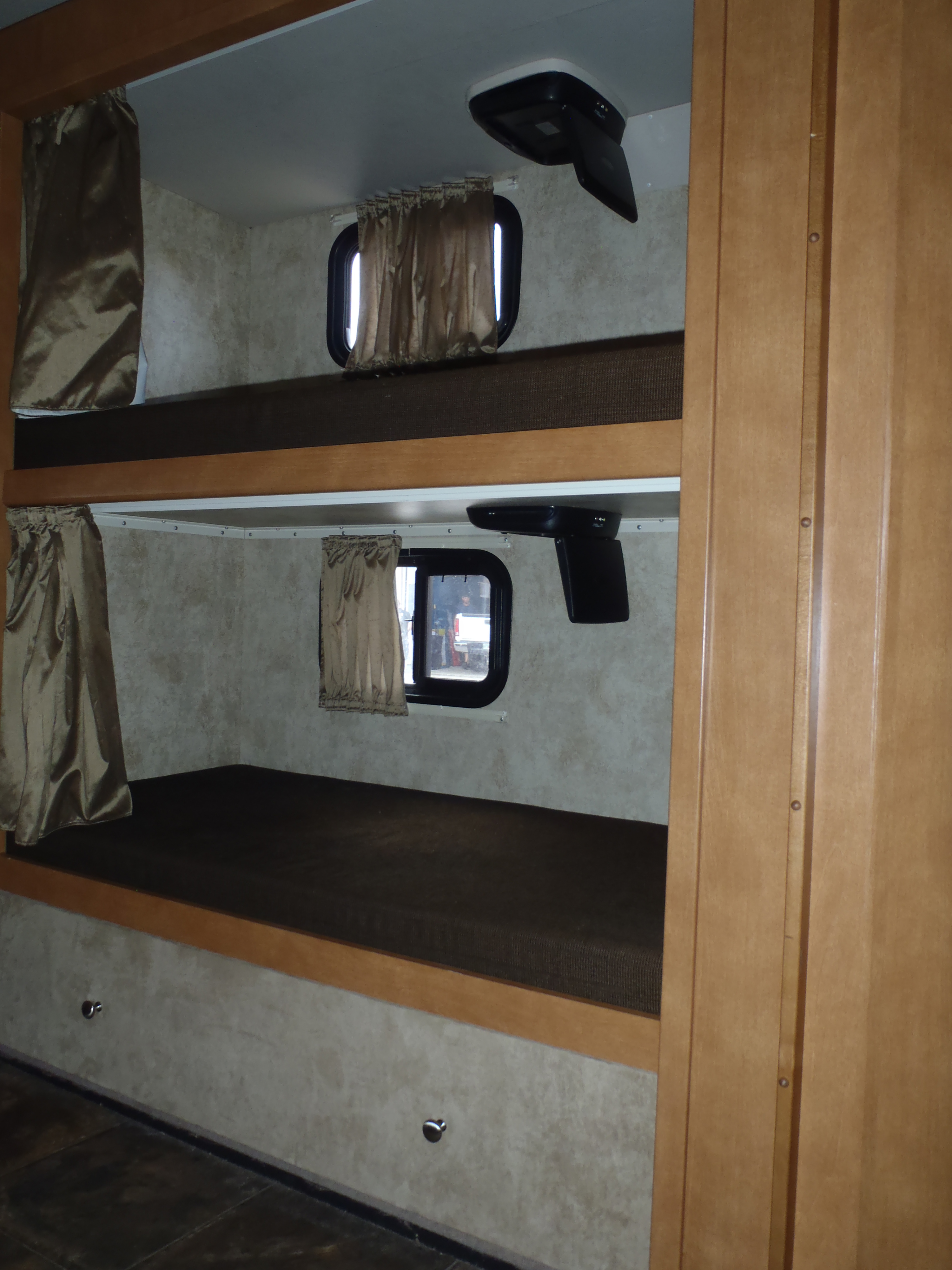 RV rental interior shows stacked bunk beds with windows & curtains, plus a mounted media screen for comfort during travel.. Winnebago Sunstar 2012