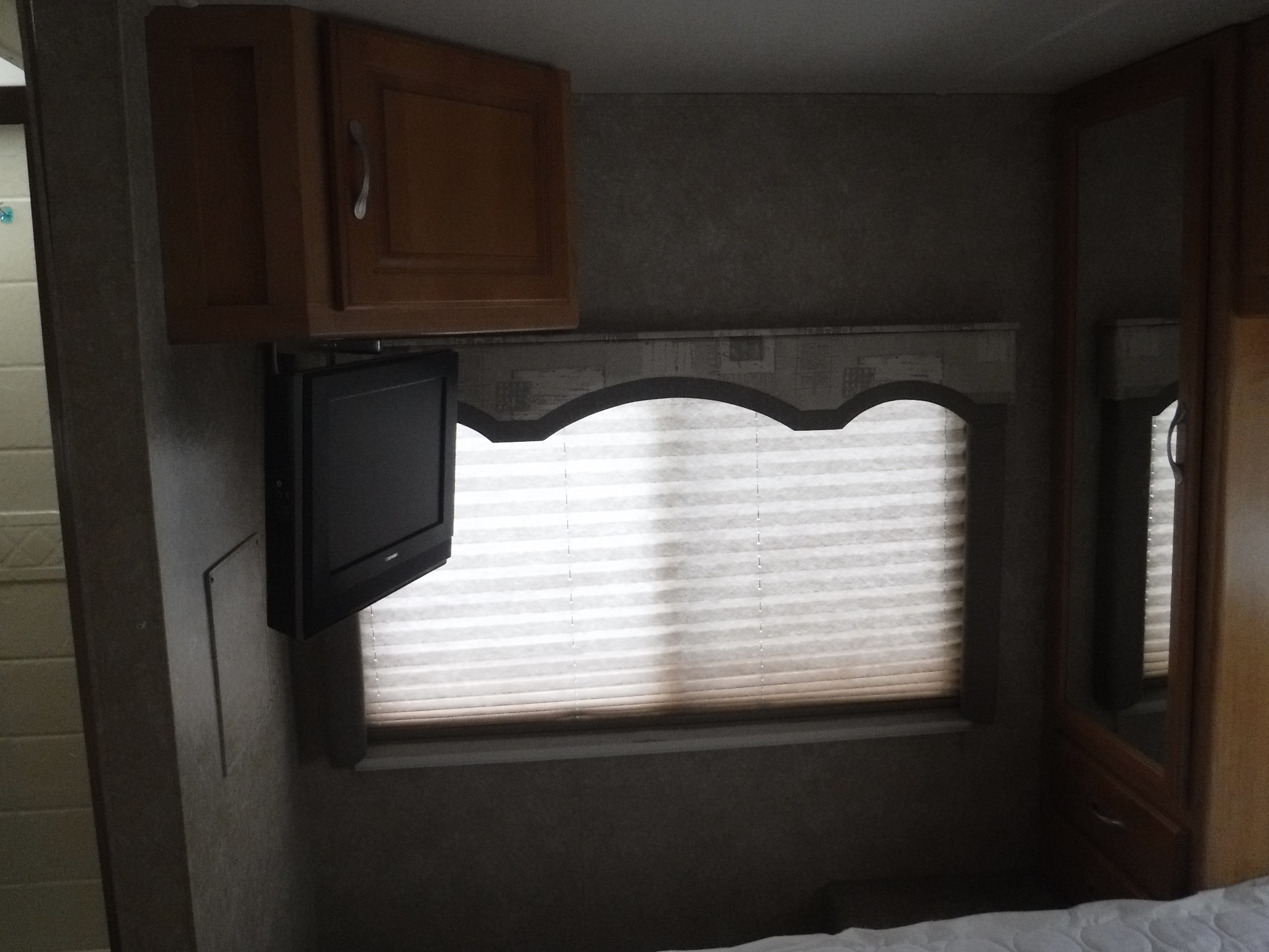 RV rental bedroom: cozy interior with wall-mounted TV, wooden cabinets, window blinds, and mirrored closet.. CHATEAU SPORT 2007