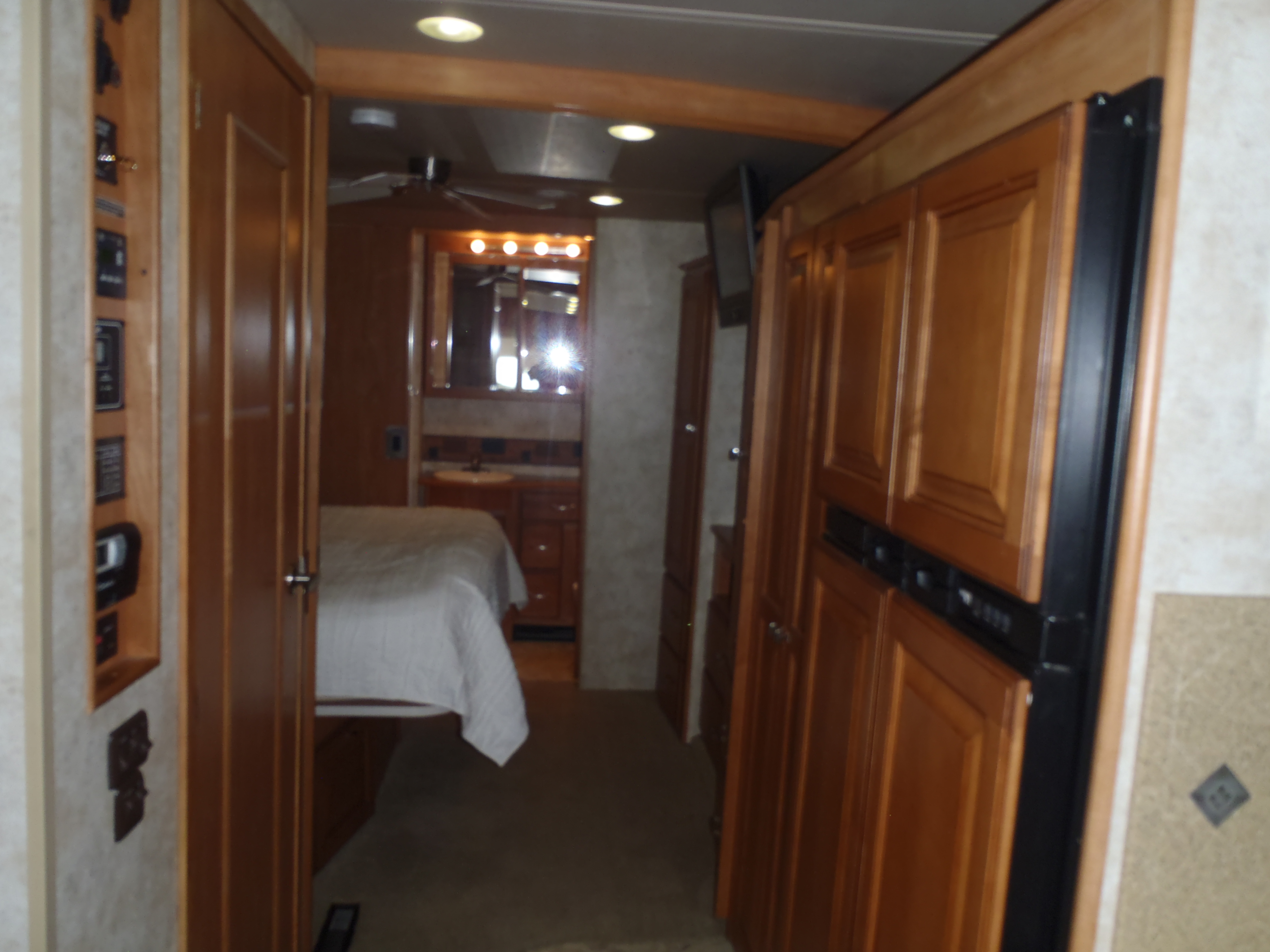 This RV rental interior features a functional layout: hallway to a cozy bedroom, bathroom vanity, kitchen with refrigerator.. Itasca Suncruiser 2017
