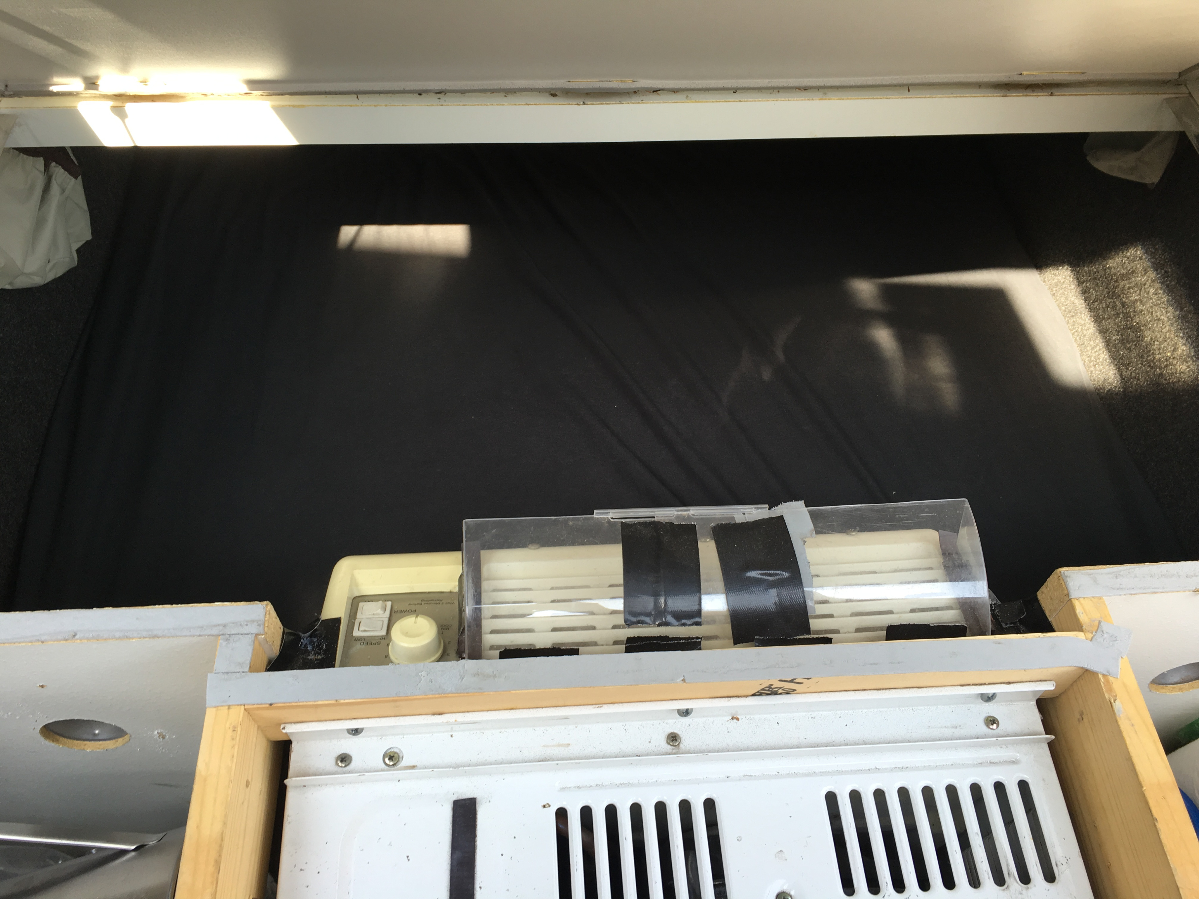 RV rental interior with a portable AC unit at the foot of the bed, illuminated by sunlight from above.. Little Guy 4 Wide 2008