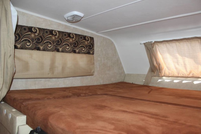 RV rental interior: A comfy bed, patterned valance, and window provide a cozy sleeping space.. Forest River Coachmen Freelander 2013