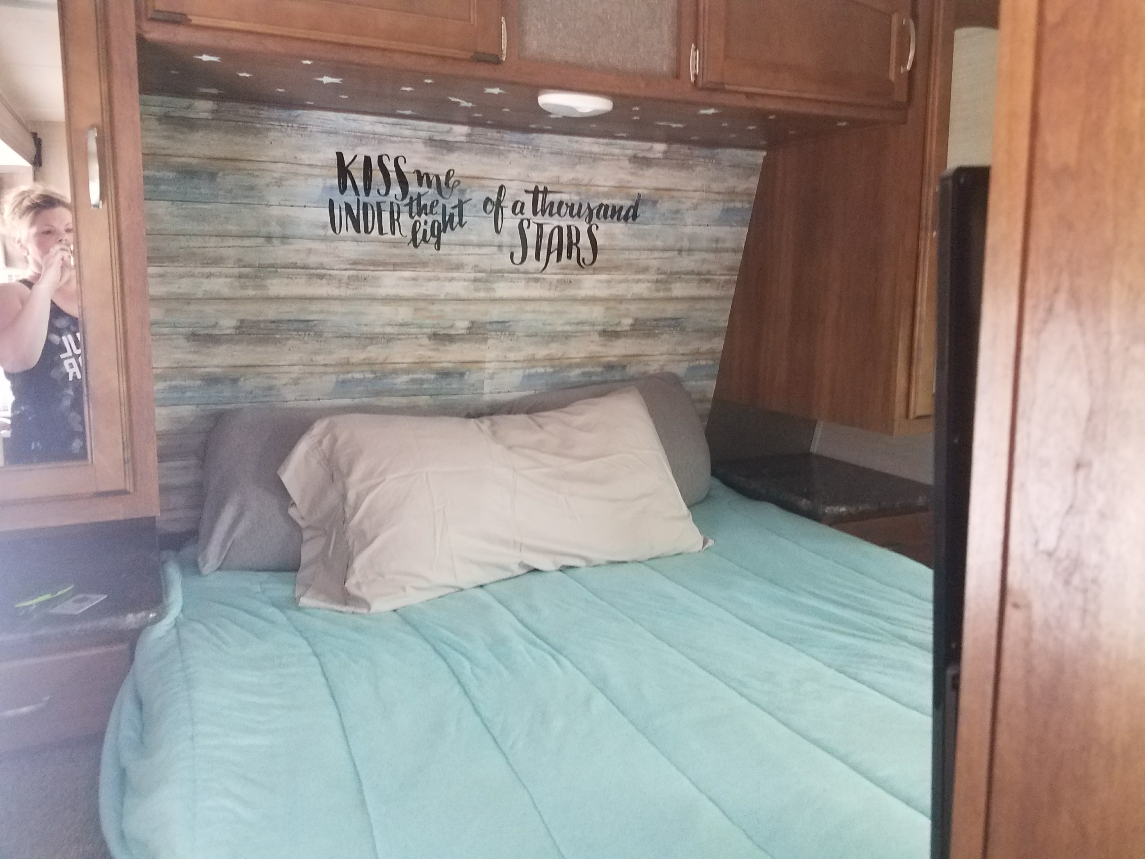 Cozy RV rental bedroom with unique "KISS me UNDER the light of a thousand STARS" headboard and soft blue bedding.. Keystone RV Springdale 2017