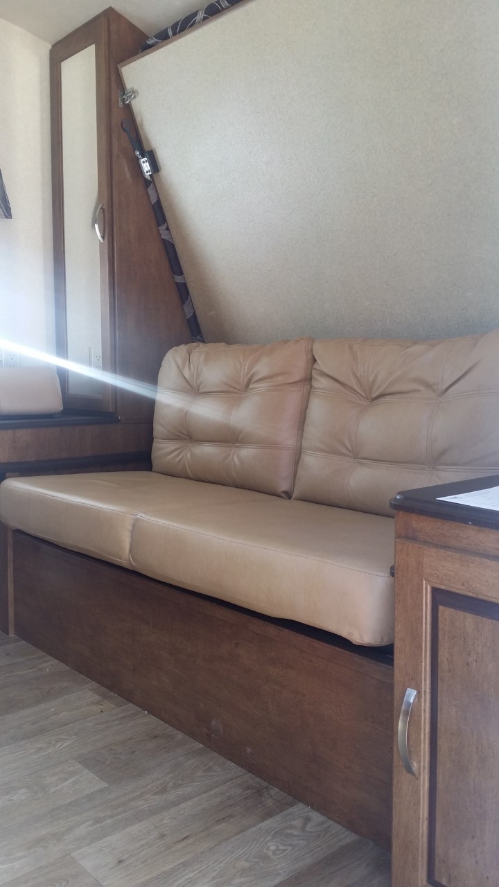 Comfortable tan sofa in an RV rental, possibly converts to a bed. Ideal for relaxing after travel.. Forest River Salem Cruise Lite 2018