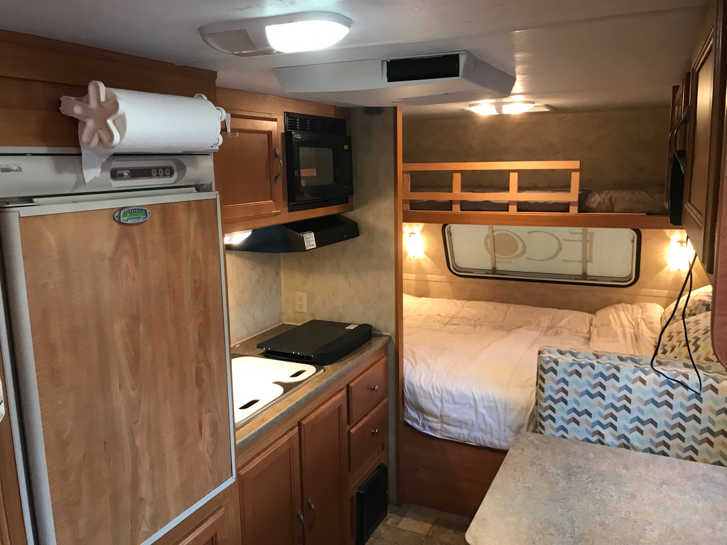 Cozy RV rental interior with kitchen amenities like a fridge, microwave, sink, and comfy sleeping areas including bunk beds.. Dutchman Eco 2010