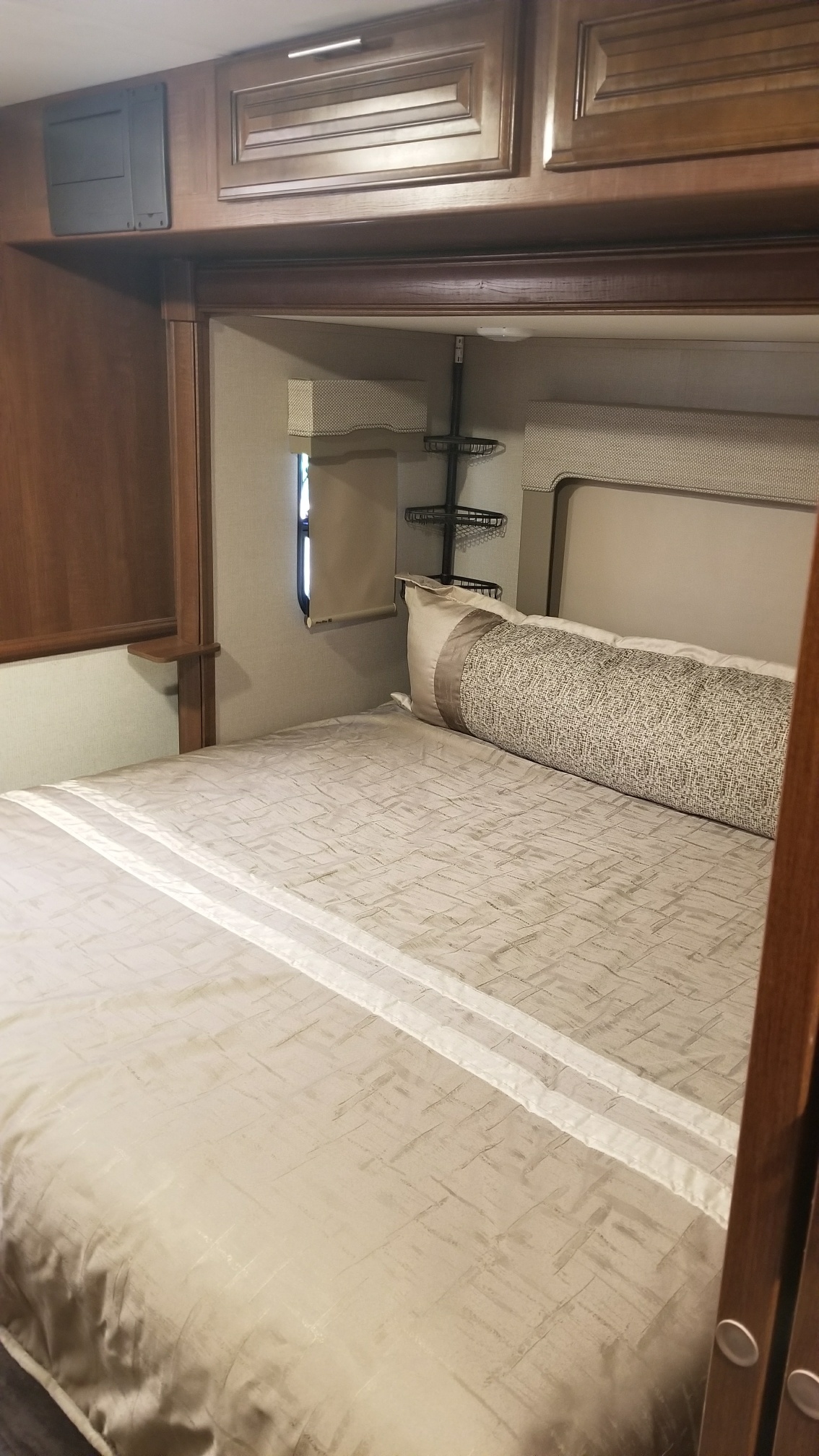Experience comfort in this RV rental bedroom, featuring a spacious bed with light bedding, wood cabinetry, and a window for natural light.. Forest River Georgetown 2017