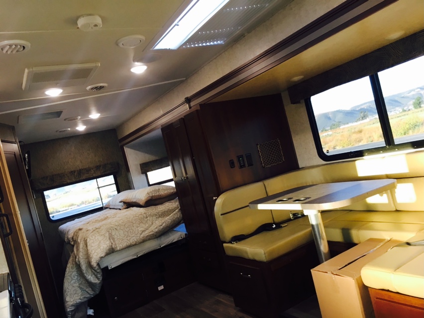 RV rental interior featuring a cozy bed, dinette with table, and views of nature through large windows.. Mercedes Benz Forest River Forester 2017