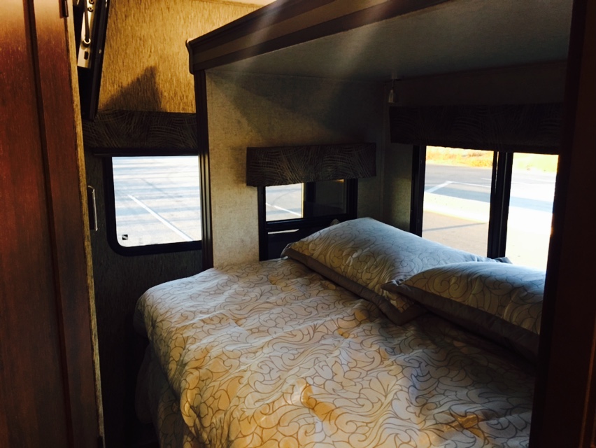 RV rental interior showcasing a comfortable bedroom with patterned bedding and bright windows.. Mercedes Benz Forest River Forester 2017