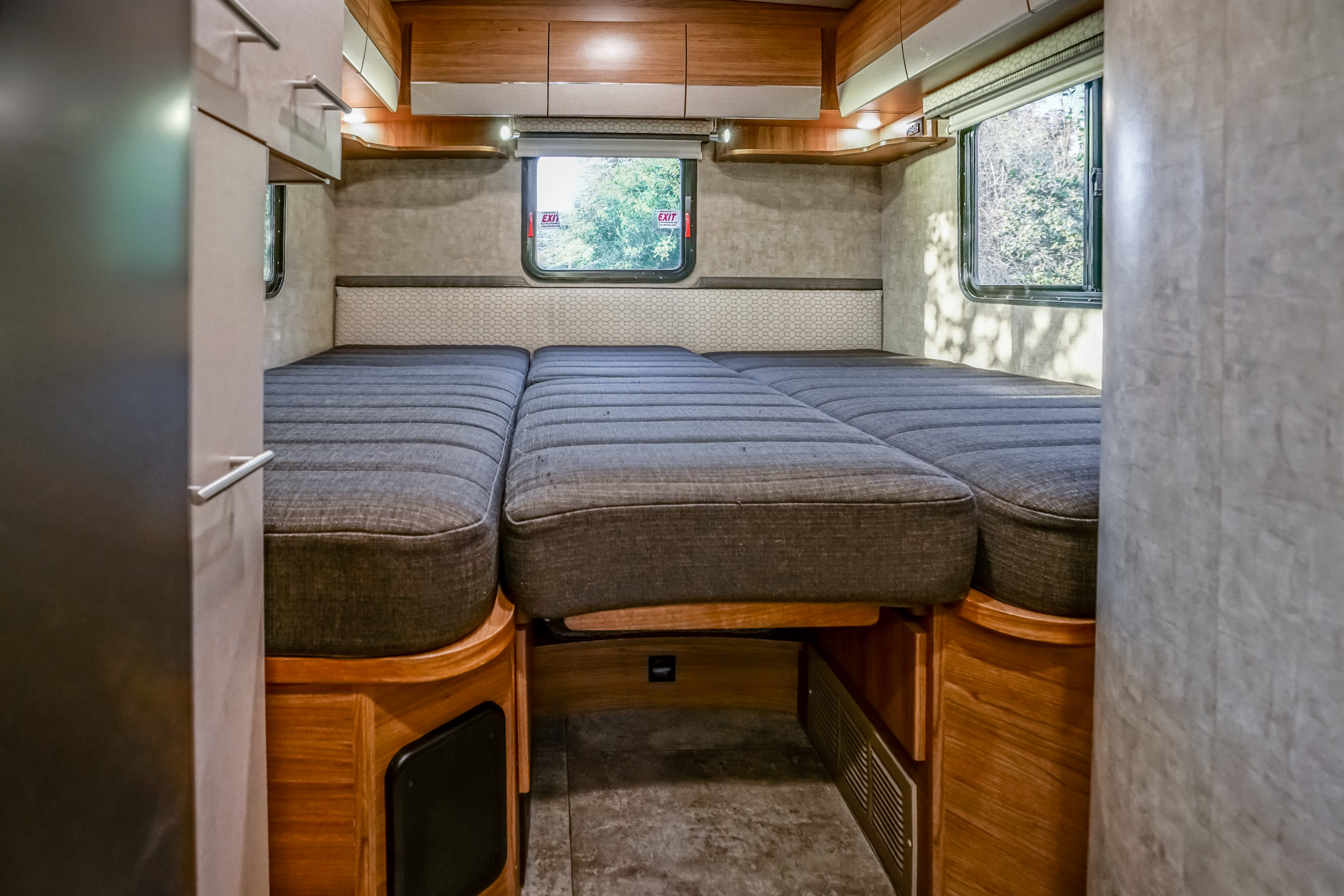 Cozy RV rental interior featuring a versatile gray bed and wood cabinetry, perfect for comfortable road trips.. Winnebago View 2018