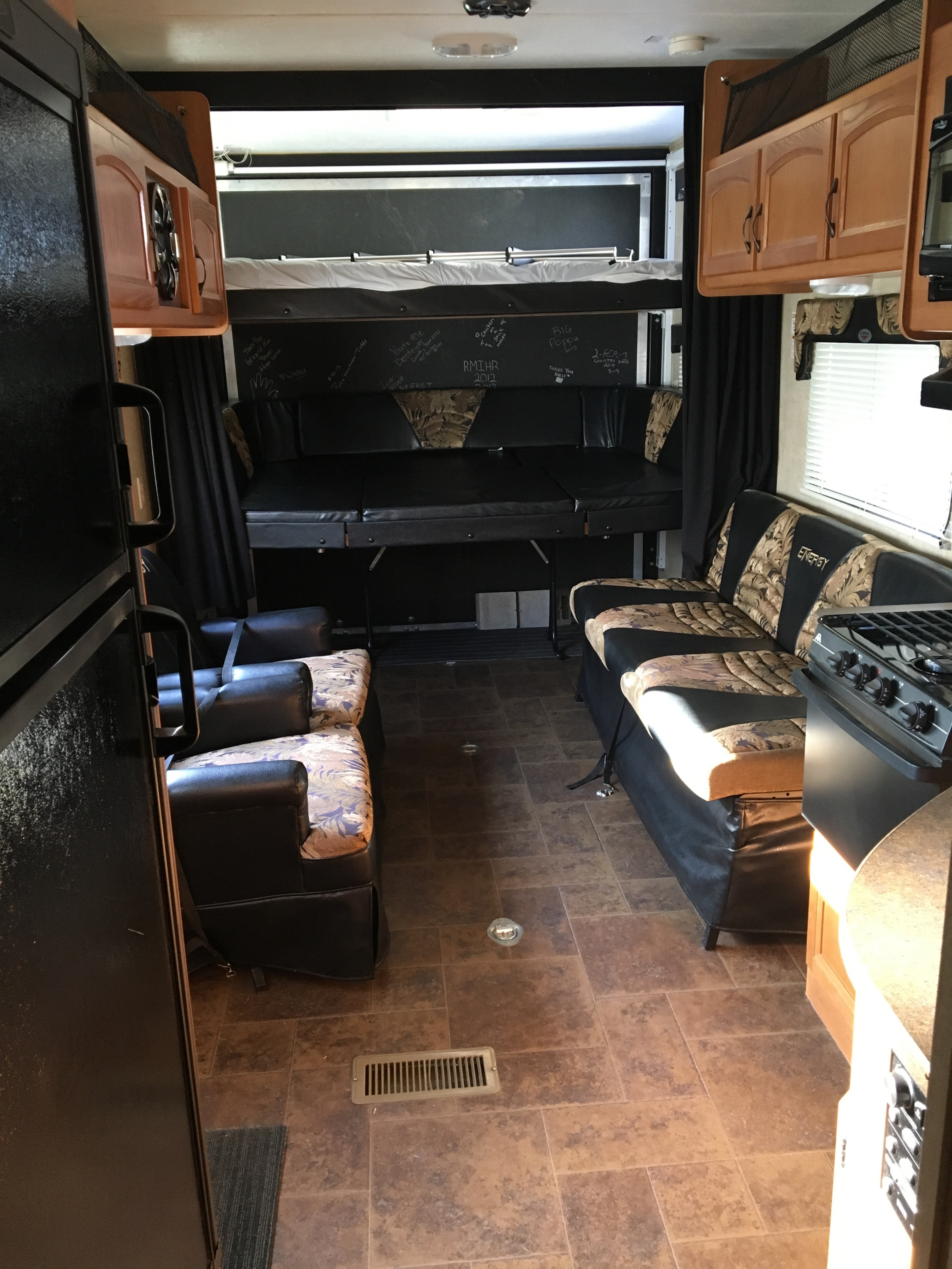 RV rental's flexible interior: toy hauler garage, convertible seating/bed, kitchen, fridge & recliners visible.. Keystone Energy Camper 2012