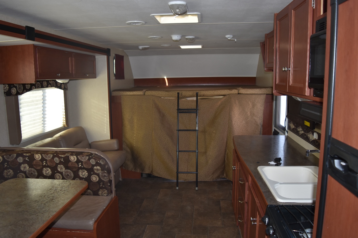 RV rental interior: kitchen, dinette, sofa, and bunk bed with privacy curtain and ladder. Ideal for travel.. Winnebago ITASCA 2014