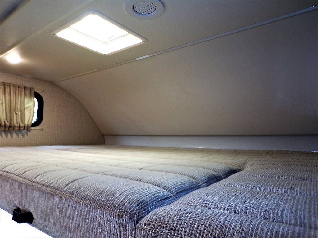 Inside an RV rental: a cozy sleeping area featuring a patterned mattress, window, and ceiling features for comfortable travel.. Winnebago Minnie Winnie 2018