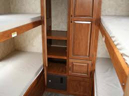 RV rental bunkhouse featuring padded twin bunks on each side and a central wood storage unit. Ideal for families.. Keystone Bullet 2013