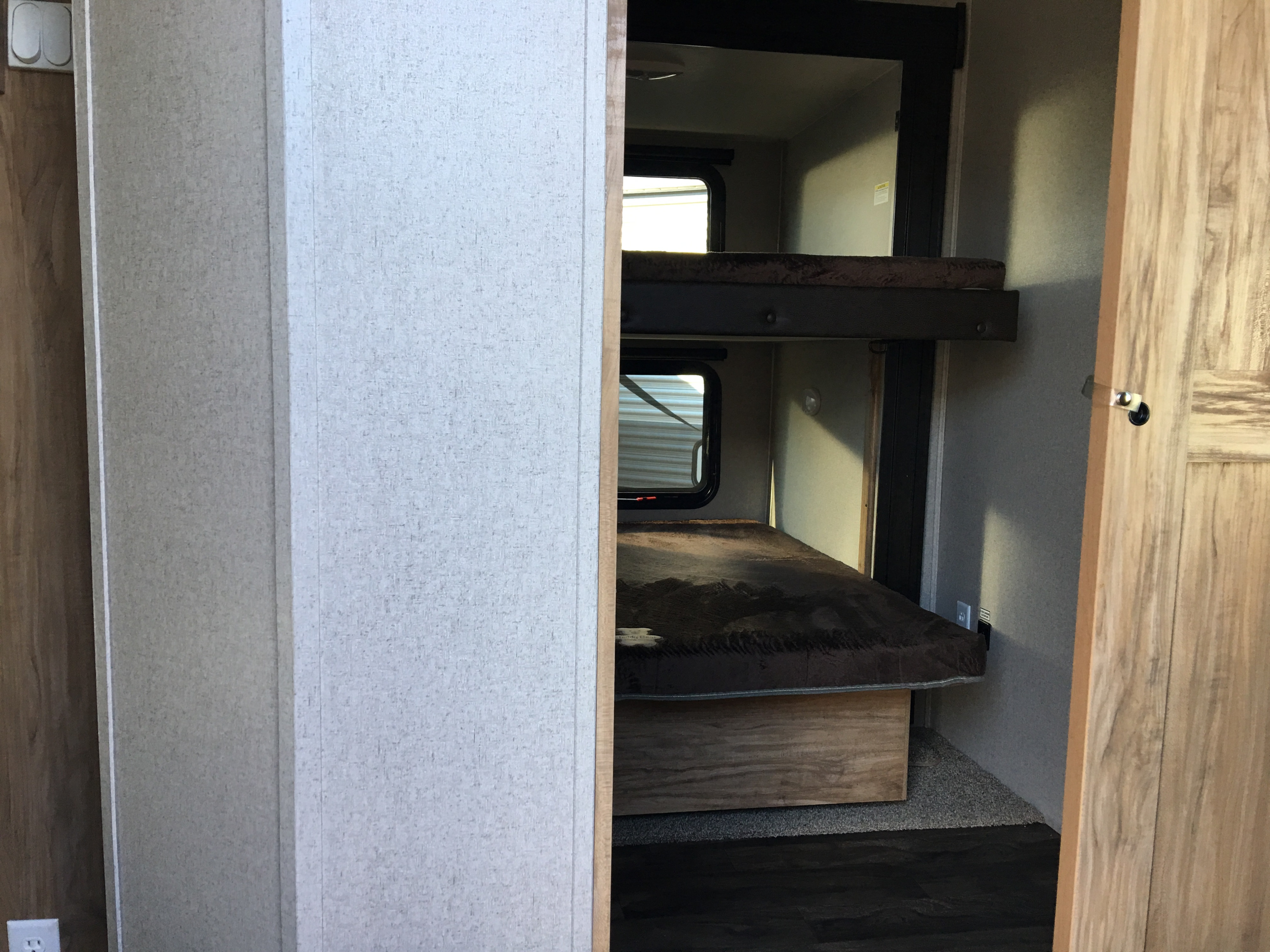 View inside an RV rental showing a sleeping area with two bunk beds, windows, and light switches.. Coachmen coachman 2018