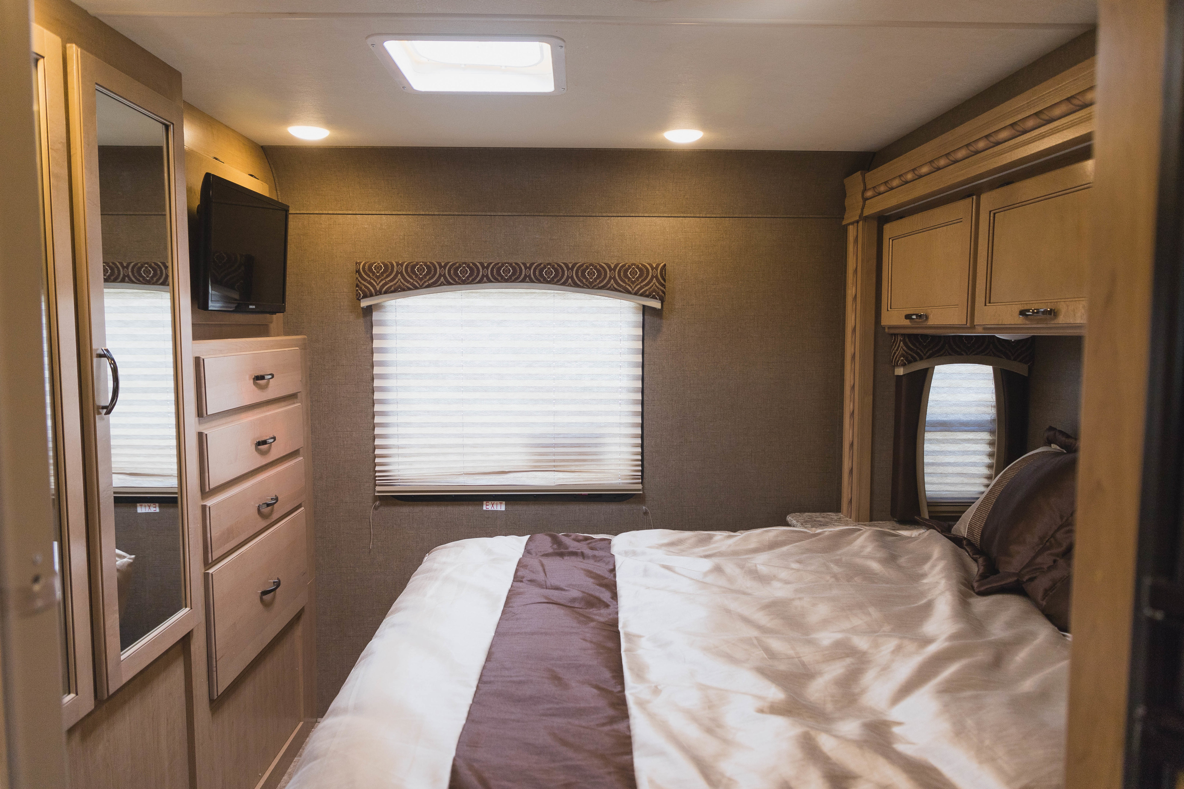 Cozy RV rental bedroom featuring a comfortable bed, window, TV, and built-in storage.. Other Other 2018