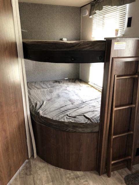 Two made-up bunk beds, one above the other, in an RV rental. A ladder provides access, showing comfortable sleeping space inside.. Heartland Pioneer 2018