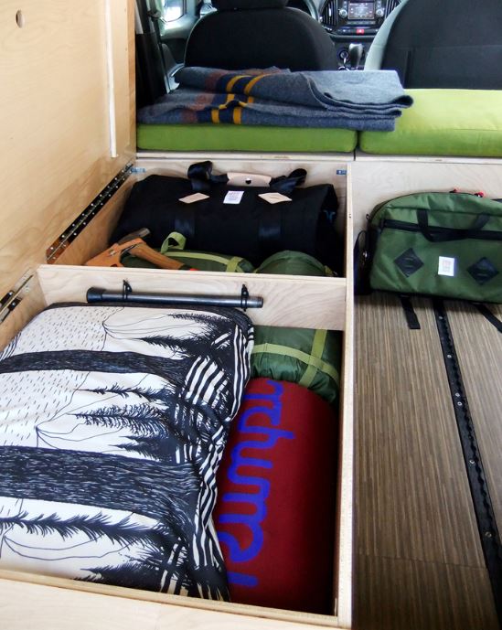 Organized RV rental interior showcasing smart storage solutions: duffels, blankets, and camping gear neatly stowed.. Ram ProMaster City 2017