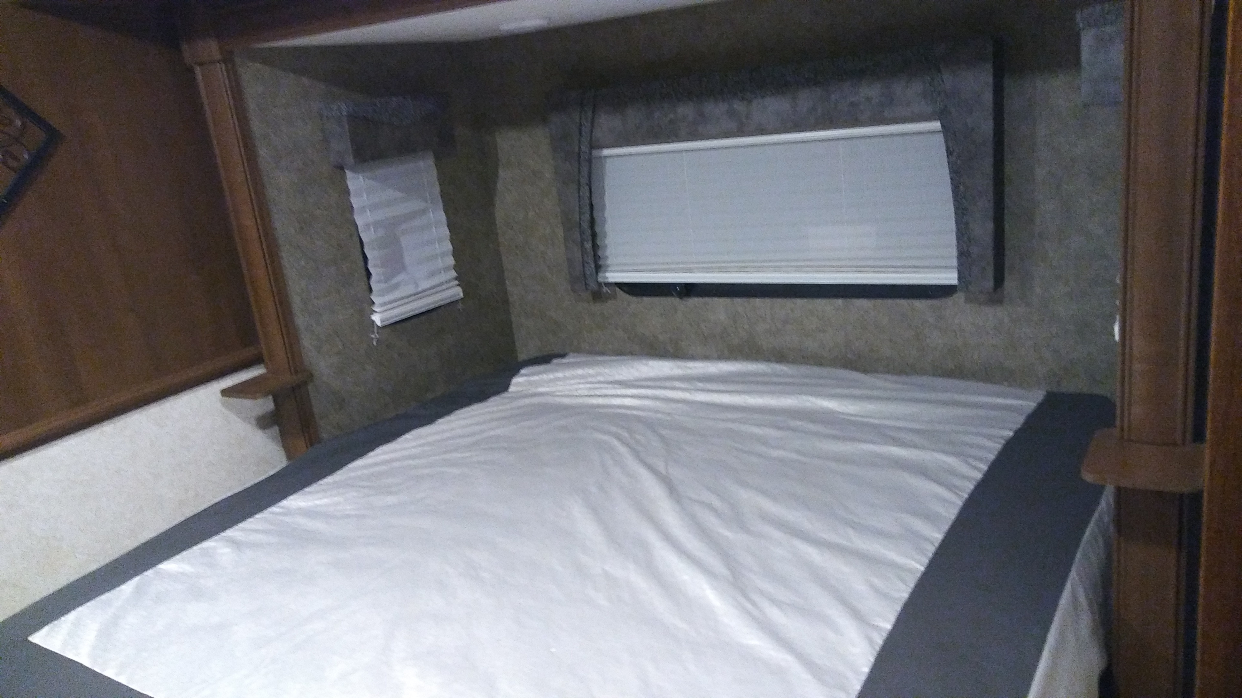 Inside this RV rental, a cozy bedroom with a bed, white sheets, dark gray trim, and two windows with white blinds.. Forest River Georgetown 2016