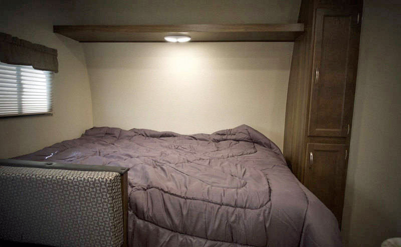 RV rental bedroom: cozy bed with purple comforter, window, and cabinet for comfortable travels.. Riverside Rv Dream 175BH 2018
