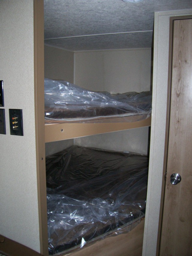 Compact RV rental sleeping area featuring two bunk beds with mattresses still in protective plastic.. Palomino Puma 2017