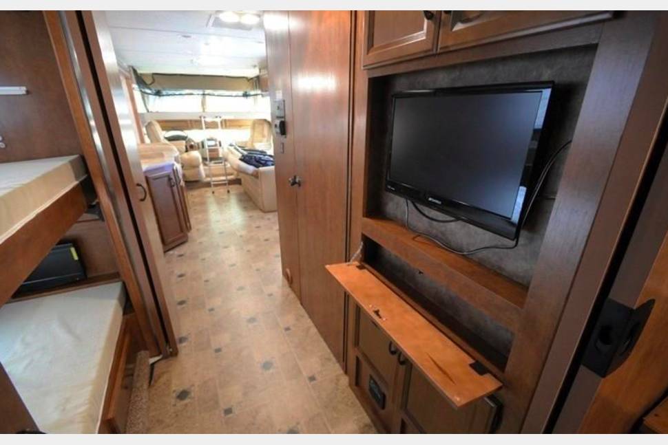 Spacious RV rental interior featuring bunk beds, a TV, and a cozy living area. Perfect for family adventures.. Thor Motor Coach Hurricane 2014