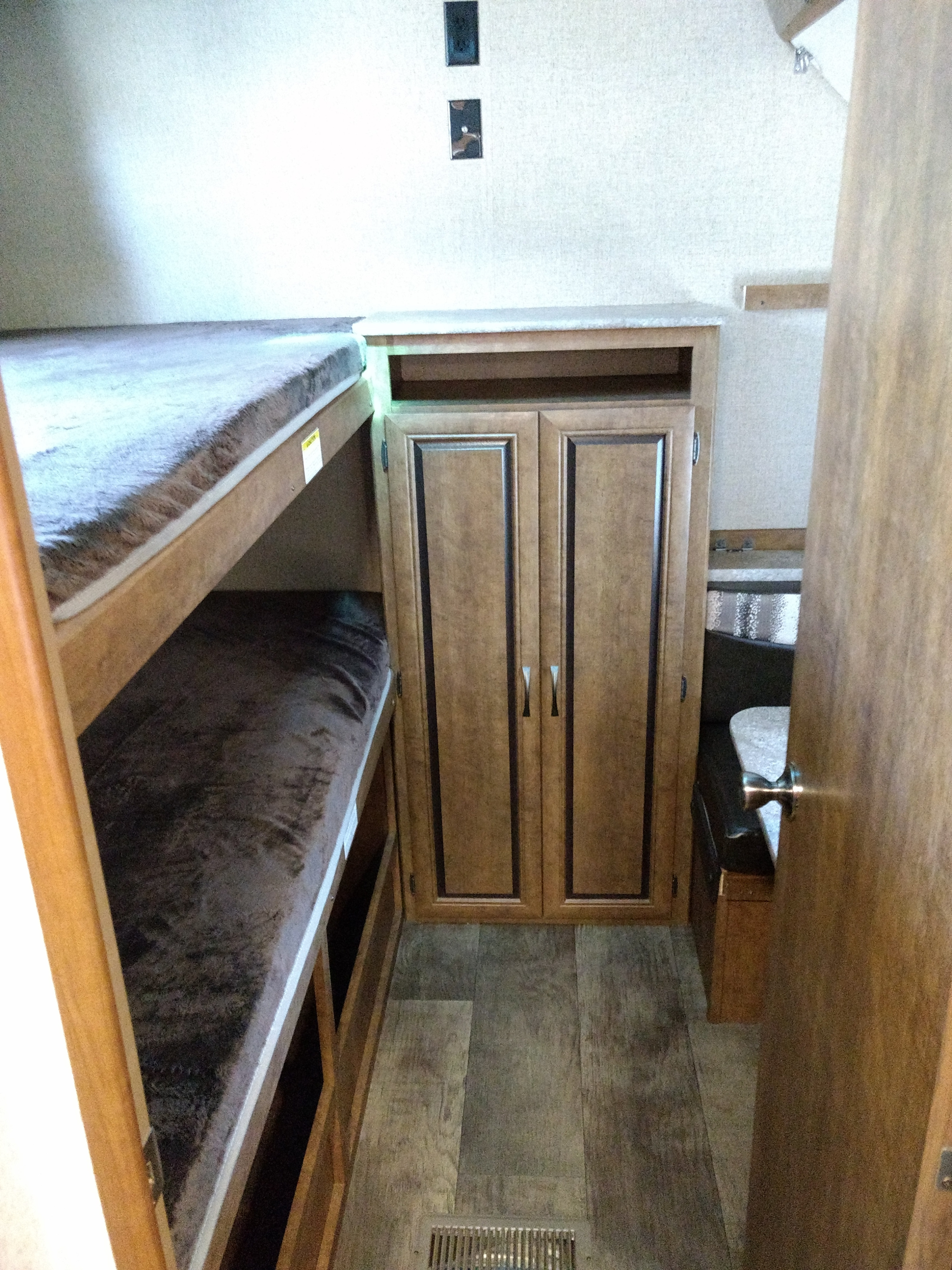 RV rental interior with wooden bunk beds, a central storage cabinet, and a small dining area, optimizing space.. Crossroads Zinger 2018