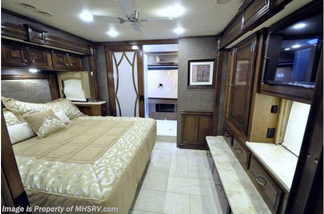Spacious, luxurious RV rental bedroom with a comfortable bed, rich wood cabinetry, and TV. Ideal for your motorhome journey.. Thor Motor Coach Tuscany 2016