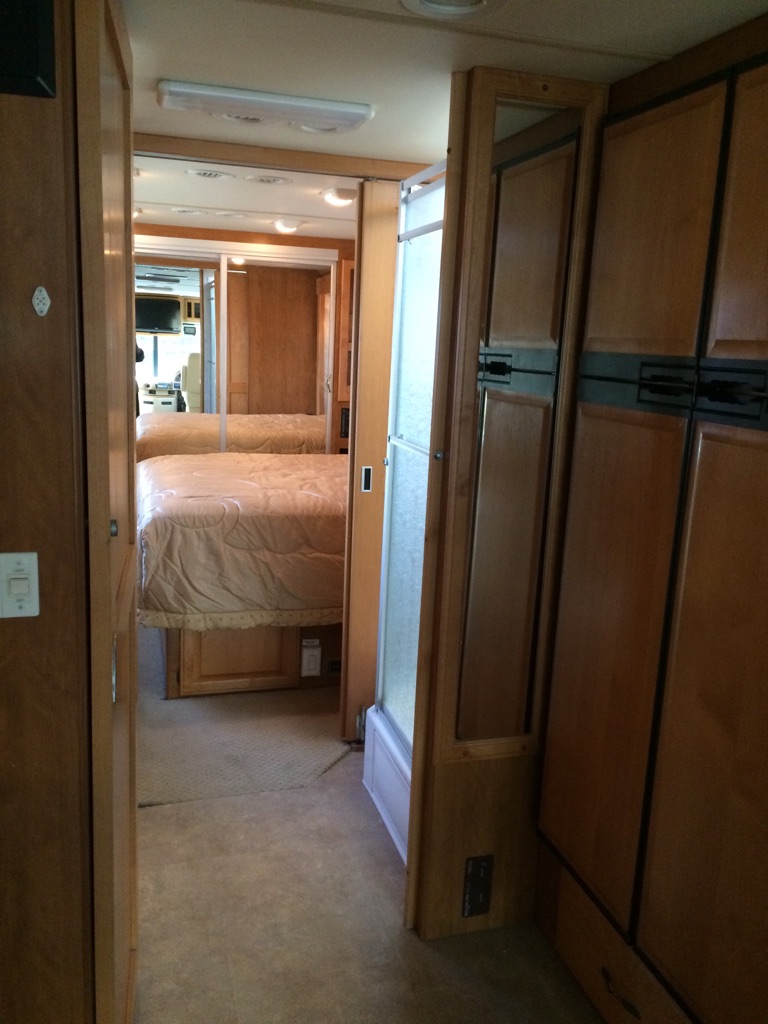 Explore this RV rental interior, featuring a cozy bedroom, compact shower, and built-in cabinetry.. Fleetwood Discovery 2005