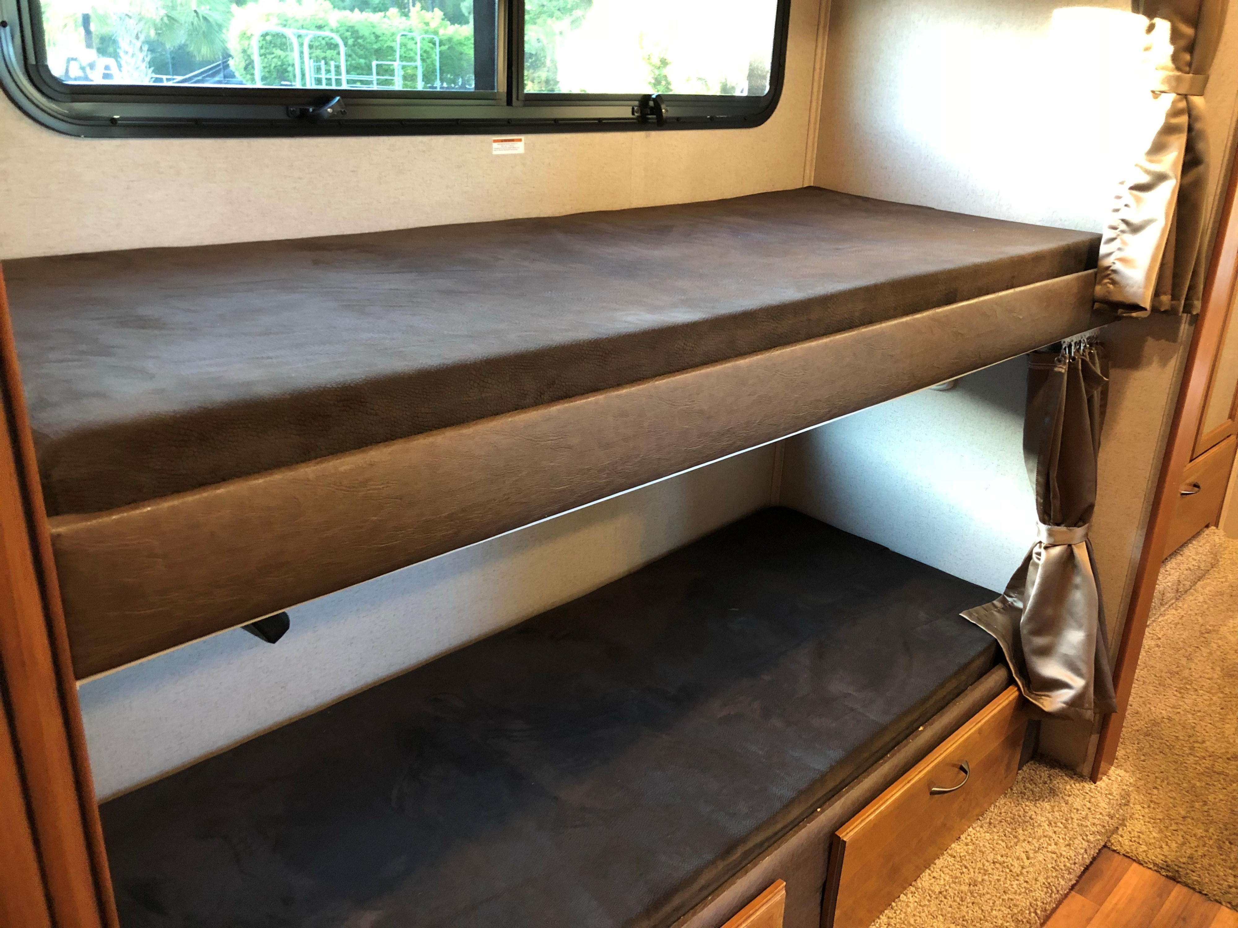 Two cozy bunk beds inside an RV rental with dark mattresses and subtle lighting, perfect for family travel.. Jayco Greyhawk 2016