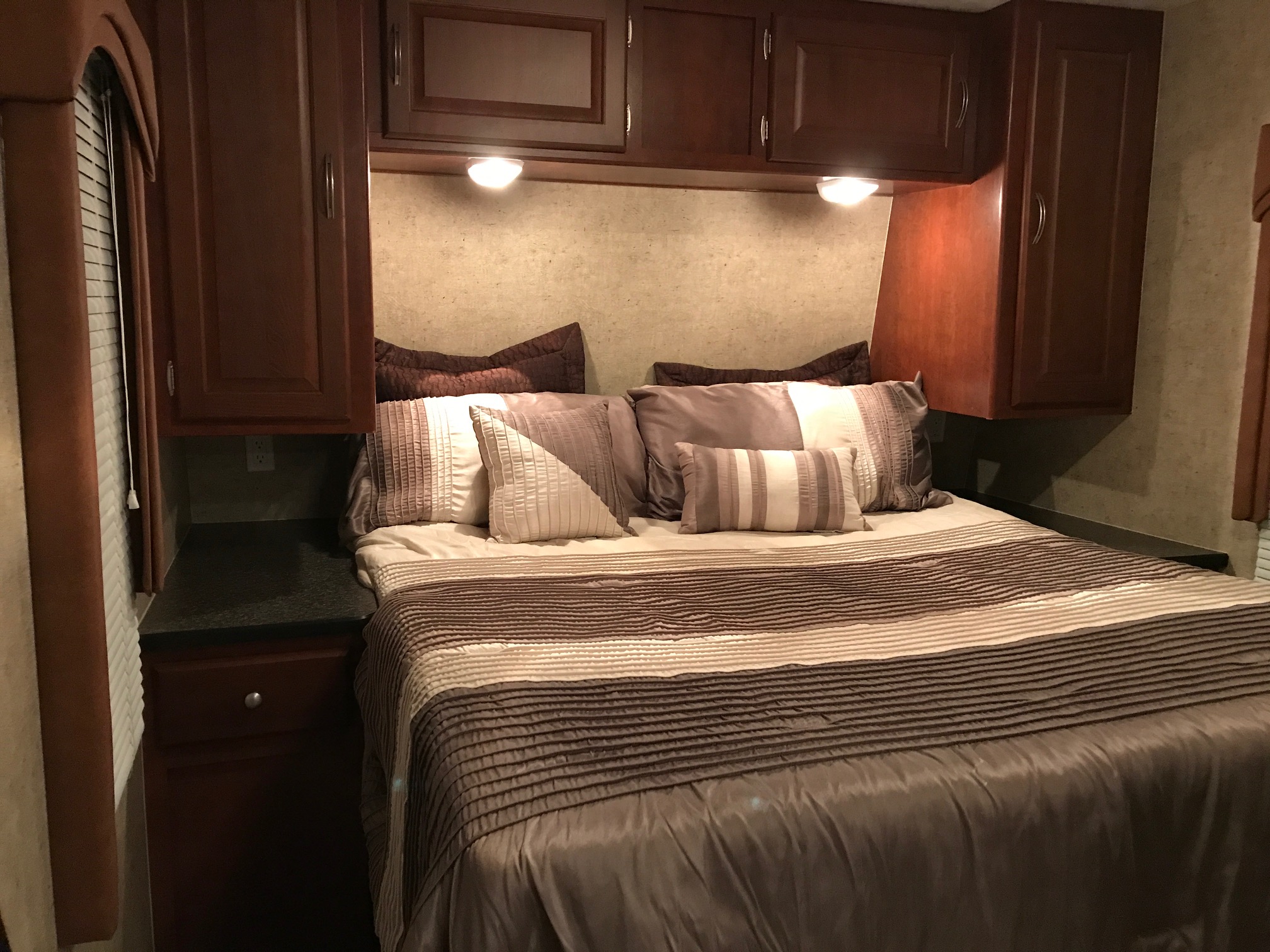 Cozy RV rental bedroom with a large bed, overhead cabinets, and reading lights. Ideal for a comfortable road trip.. Forest River Wildwood 2011