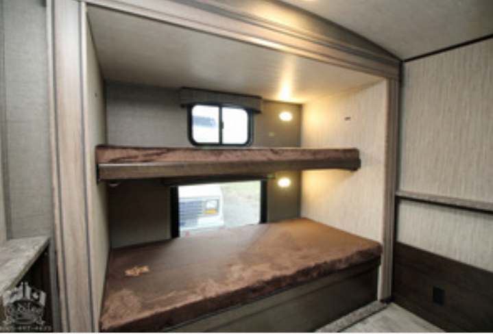 Spacious RV rental interior features comfortable bunk beds, individual windows, and reading lights for a cozy stay.. Heartland Sundance 2019