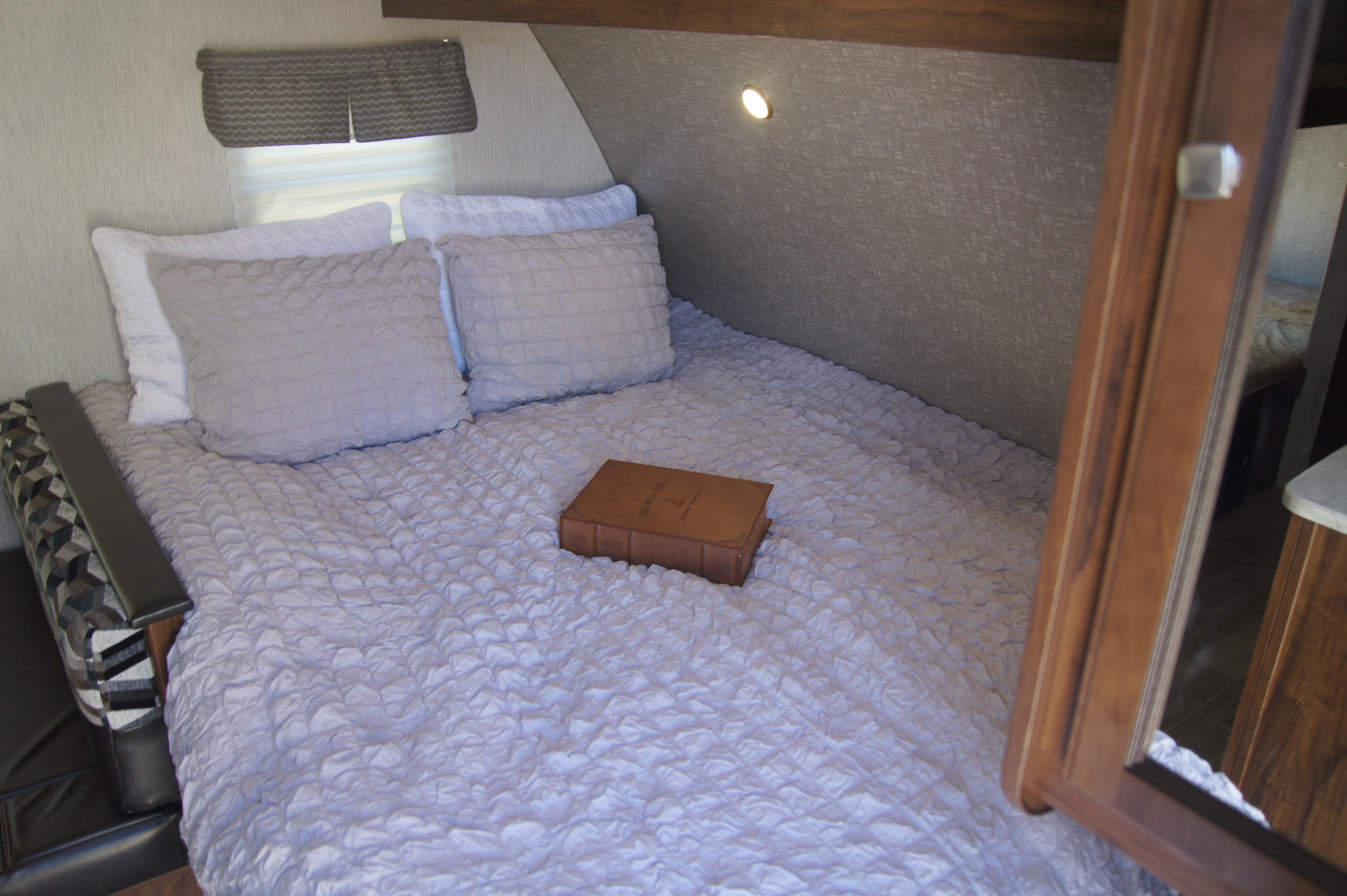 Cozy RV rental bedroom with textured bedding and built-in light, offering comfort on the go.. Heartland Other 2018