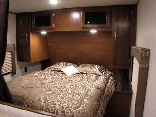 Comfortable RV rental bedroom with wooden cabinets, a cozy bed, and practical storage, ideal for travelers.. Jayco 2017 jayco bunkhouse 28 foot trailer sleeps 10 lightweight 2017
