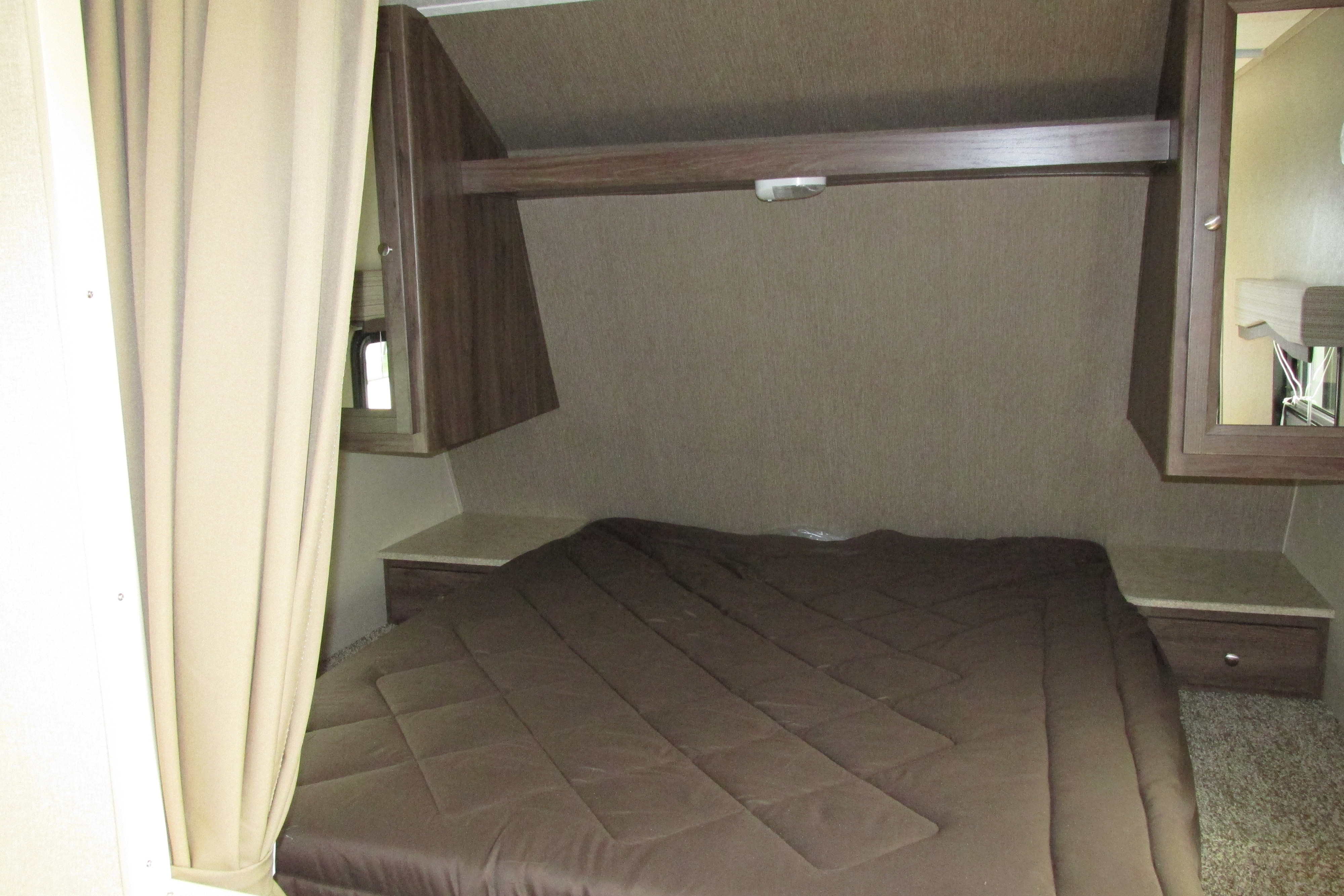 RV rental bedroom featuring a large bed with brown comforter, storage cabinets, and curtains for privacy.. Coleman 2017 coleman 28 foot bunkhouse sleeps 10 only 4500 pounds 2017