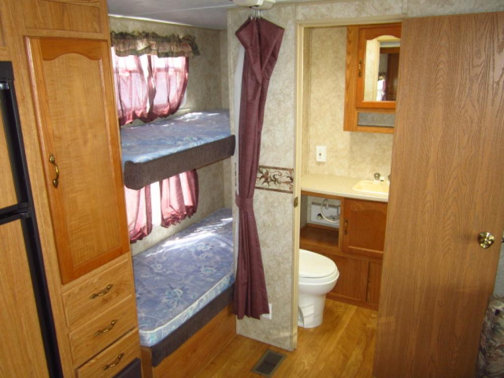 RV rental interior shows bunk beds, bathroom with sink & toilet, and wood cabinetry.. Forest River Wildwood 2005