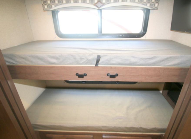 RV rental: Bright interior featuring two stacked bunk beds with mattresses. A window is above the top bunk, with a TV screen to its right.. Thor Motor Coach Hurricane 2018