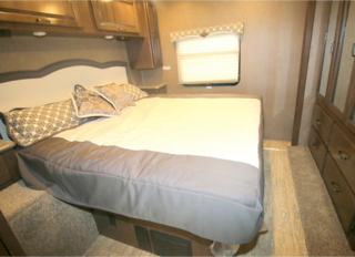 Relax in this cozy RV rental bedroom featuring a comfortable bed, ample storage, and a large window, ideal for travel.. Thor Motor Coach Hurricane 2018