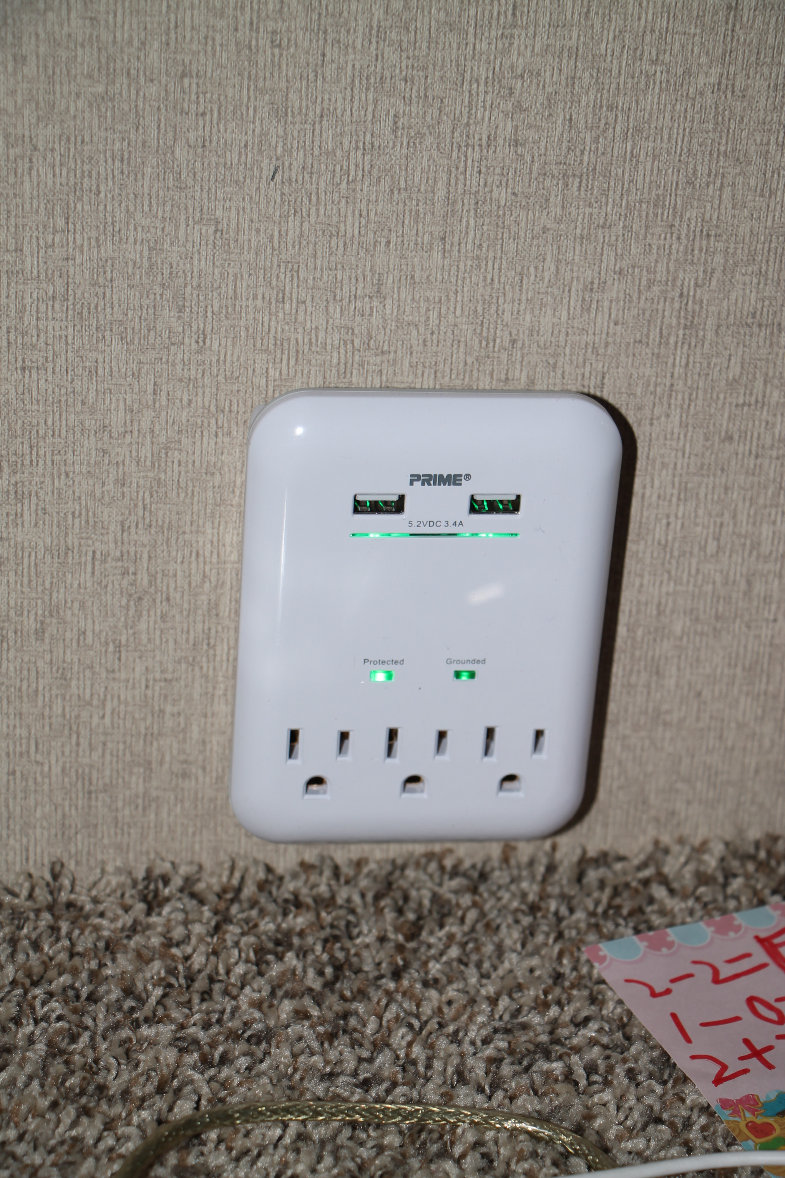 A white PRIME power strip with USB ports and AC outlets, showing green "Protected" & "Grounded" lights, in an RV rental.. Coleman Lantern 2018