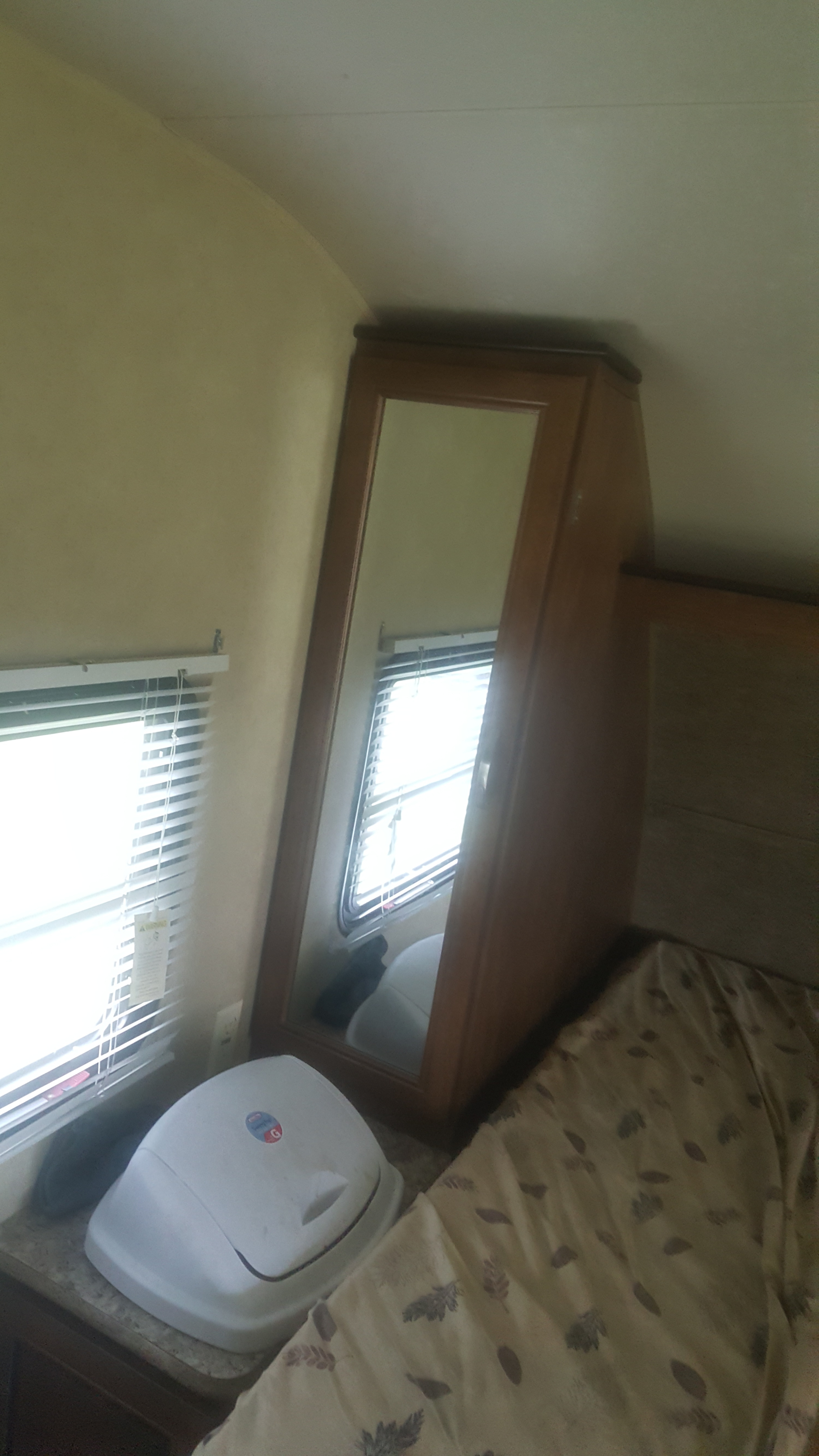 RV rental bedroom interior: bed with patterned bedding, mirrored cabinet, and bright windows with blinds.. Forest River Salem Cruise Lite 2017