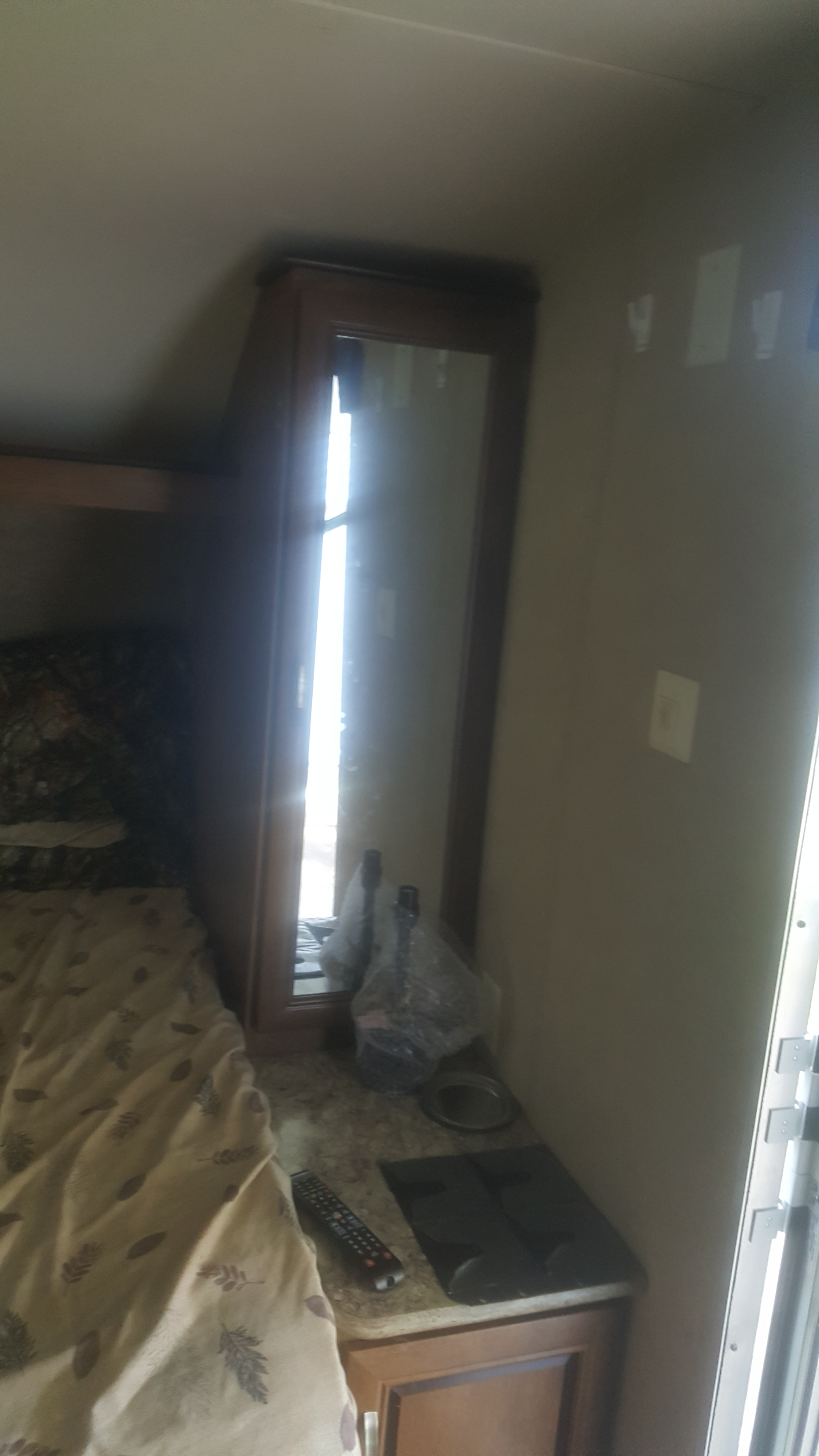 RV rental: a cozy bedroom with patterned bed, mirrored wardrobe, and compact counter with remote.. Forest River Salem Cruise Lite 2017