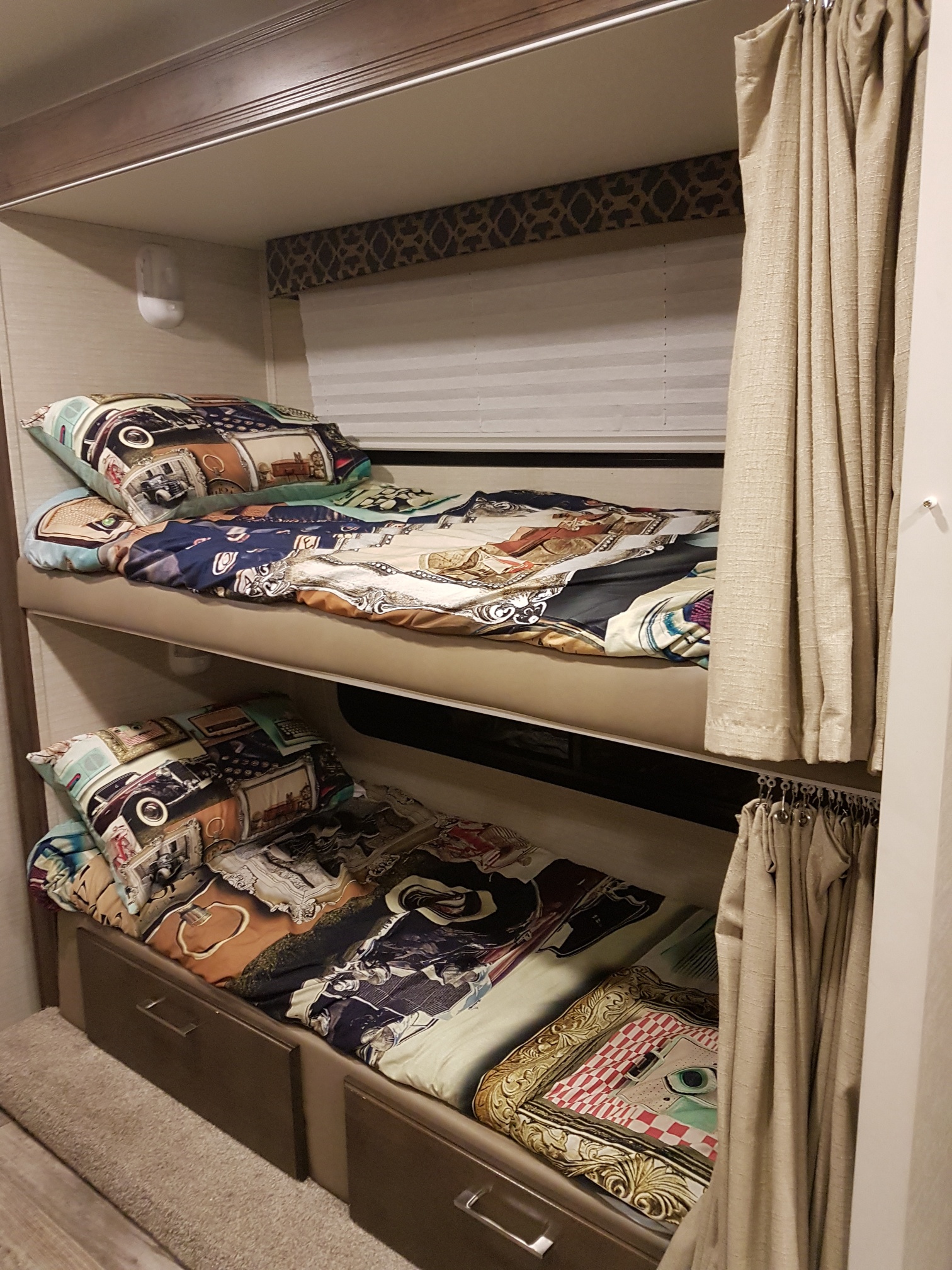 Cozy bunk beds inside an RV rental, featuring patterned bedding, window blinds, and convenient storage drawers below.. Jayco Redhawk 2018