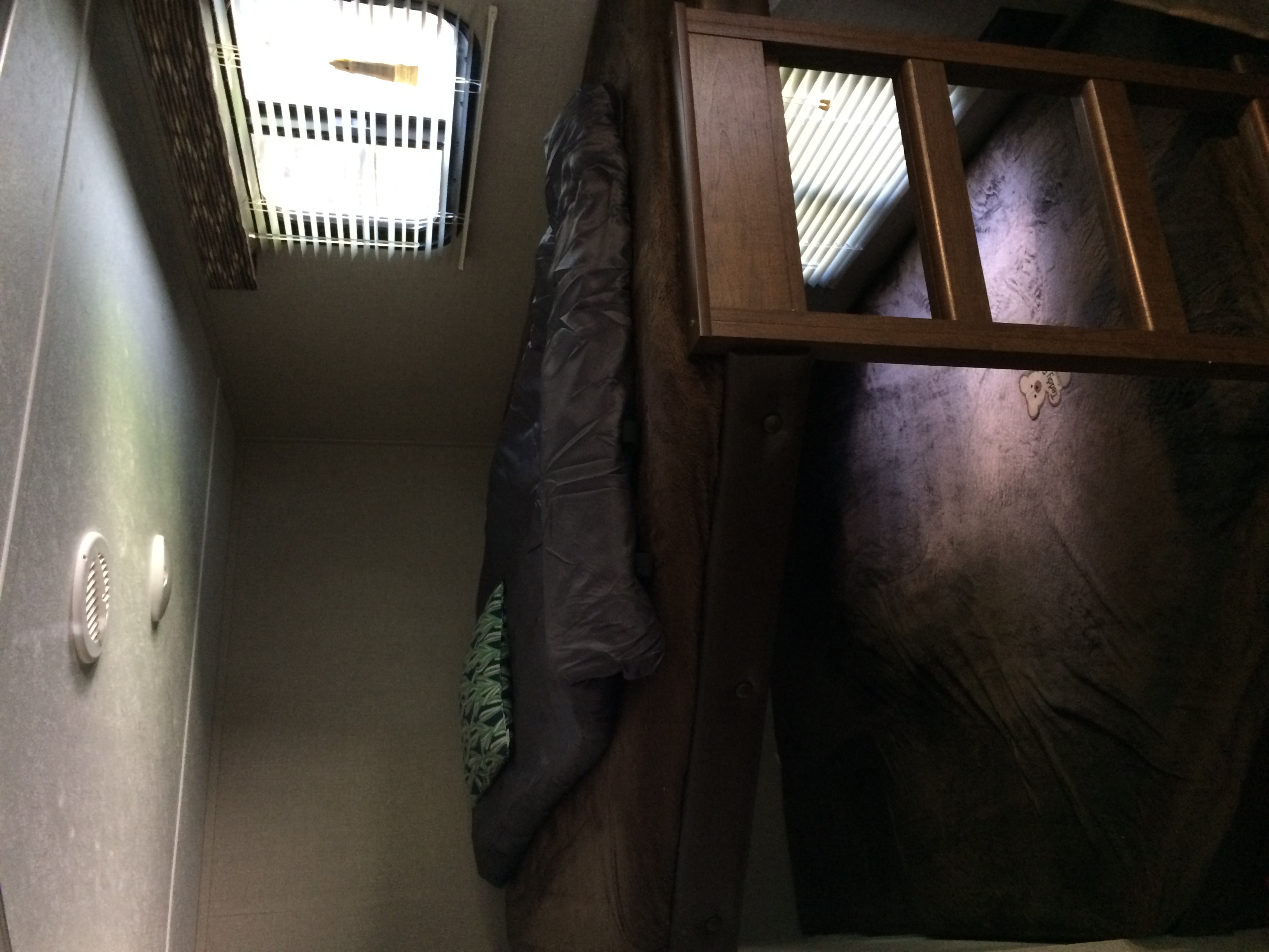 Cozy RV rental interior: A top bunk bed with sleeping bag, window with blinds, wall vents, and a teddy bear tag on the mattress.. Keystone Hideout 2017
