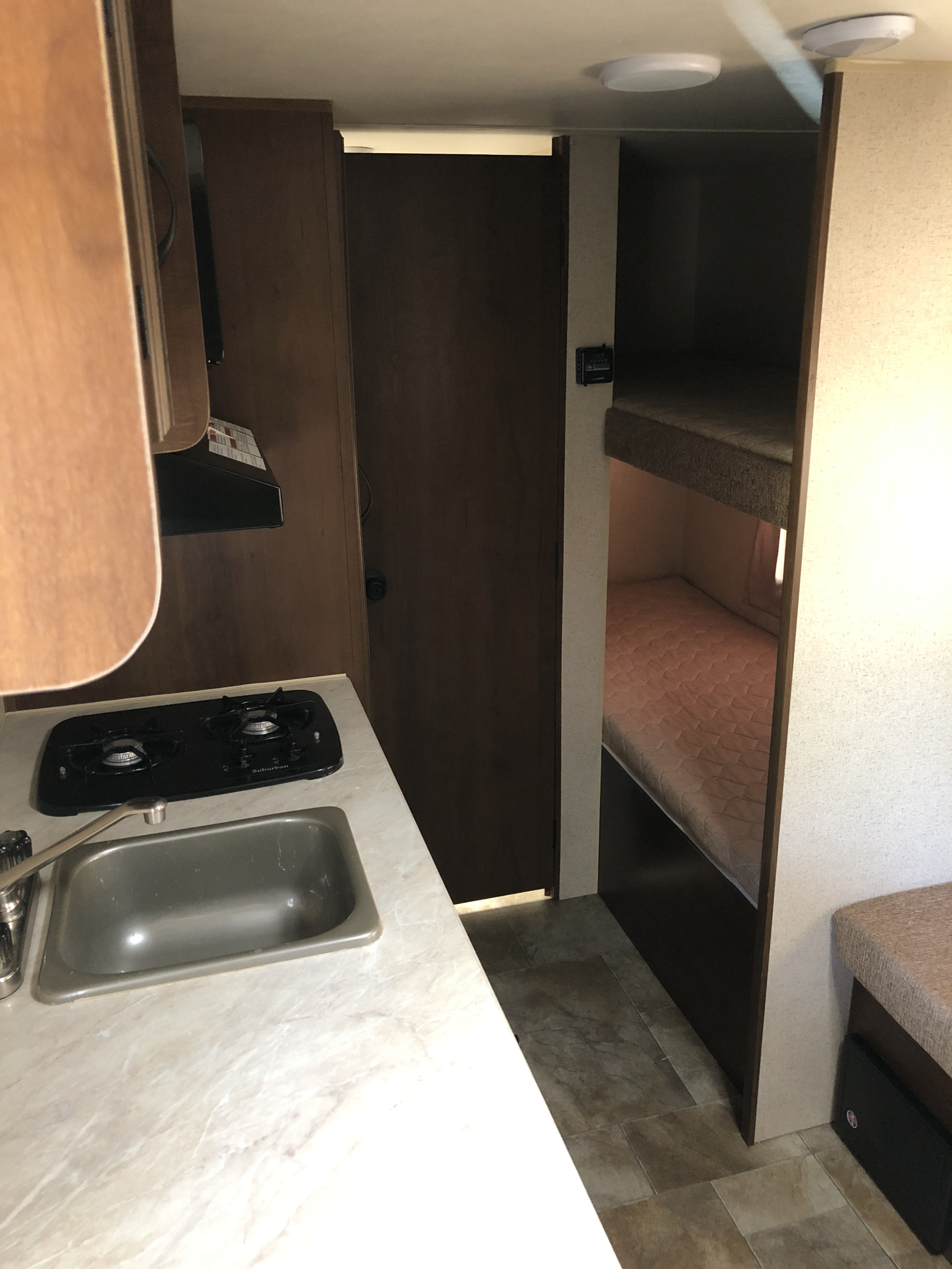 RV rental: Compact interior view with kitchen counter (sink, stove), a closed door, and comfortable bunk beds for guests.. Jayco Jay Flight SLX 2015