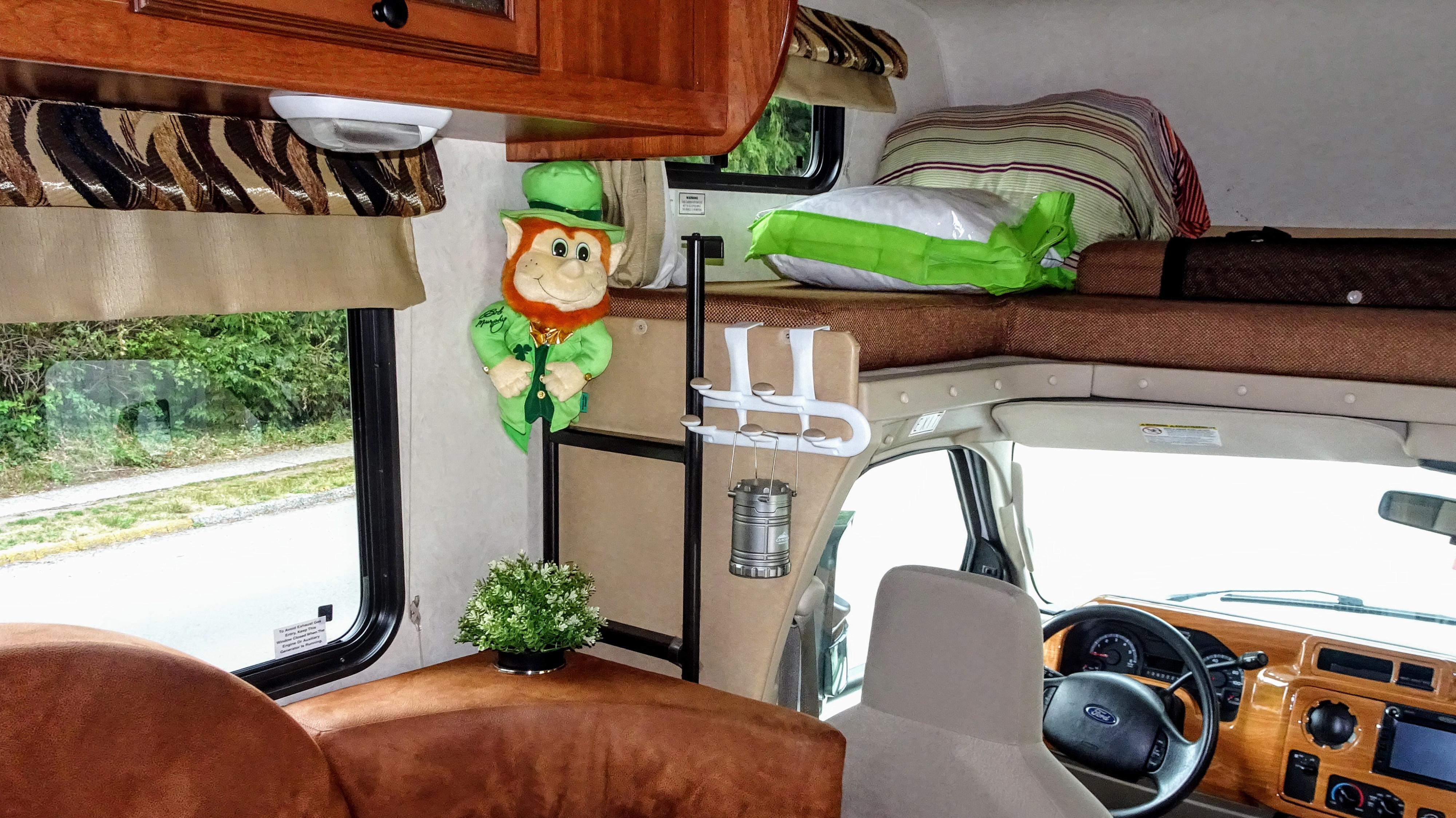 Inside an RV rental: a plush leprechaun hangs near a bunk bed, with the Ford dashboard visible towards the front.. Forest River Coachmen Leprechaun 2014