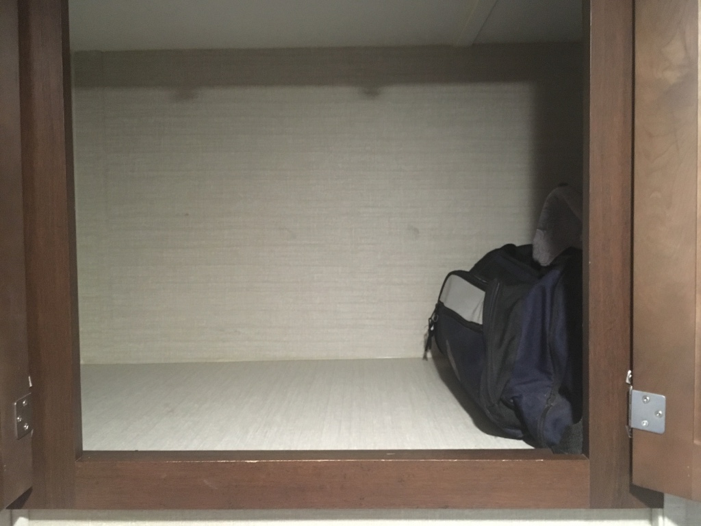 Inside an RV rental cabinet, a dark bag sits on a light shelf. Plenty of storage space for your trip.. Keystone RV Bullet Ultra Lite 2016