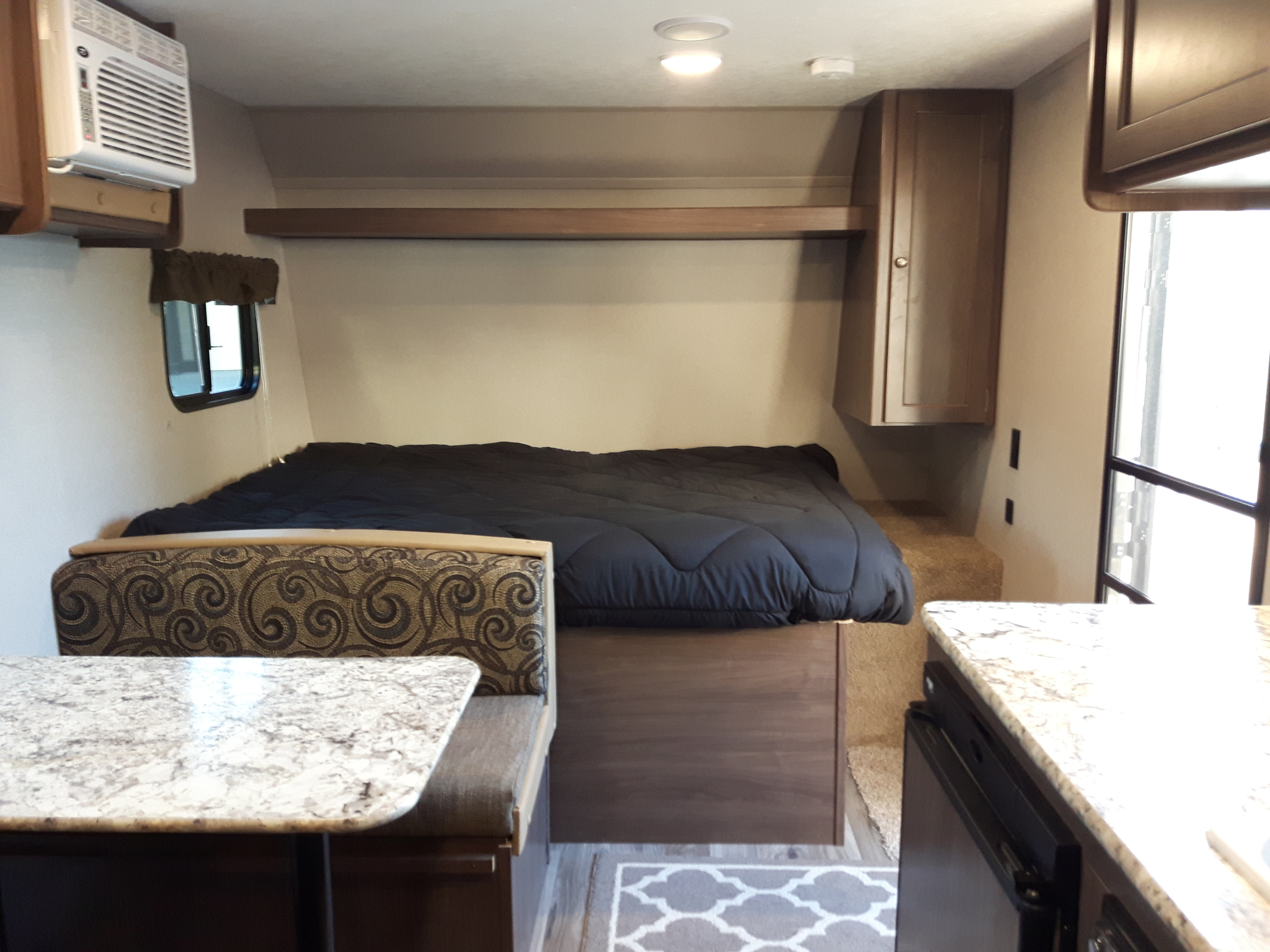 Cozy RV rental interior with a comfortable bed, dinette, and kitchen counter, ideal for your next adventure.. Keystone Hideout 2018