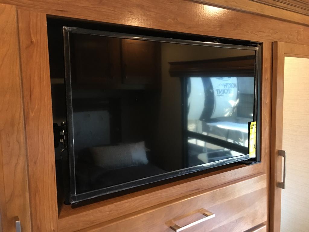 Stay entertained in your RV rental. This image shows a flat-screen TV recessed into polished wooden cabinetry.. Jayco Seneca 2019