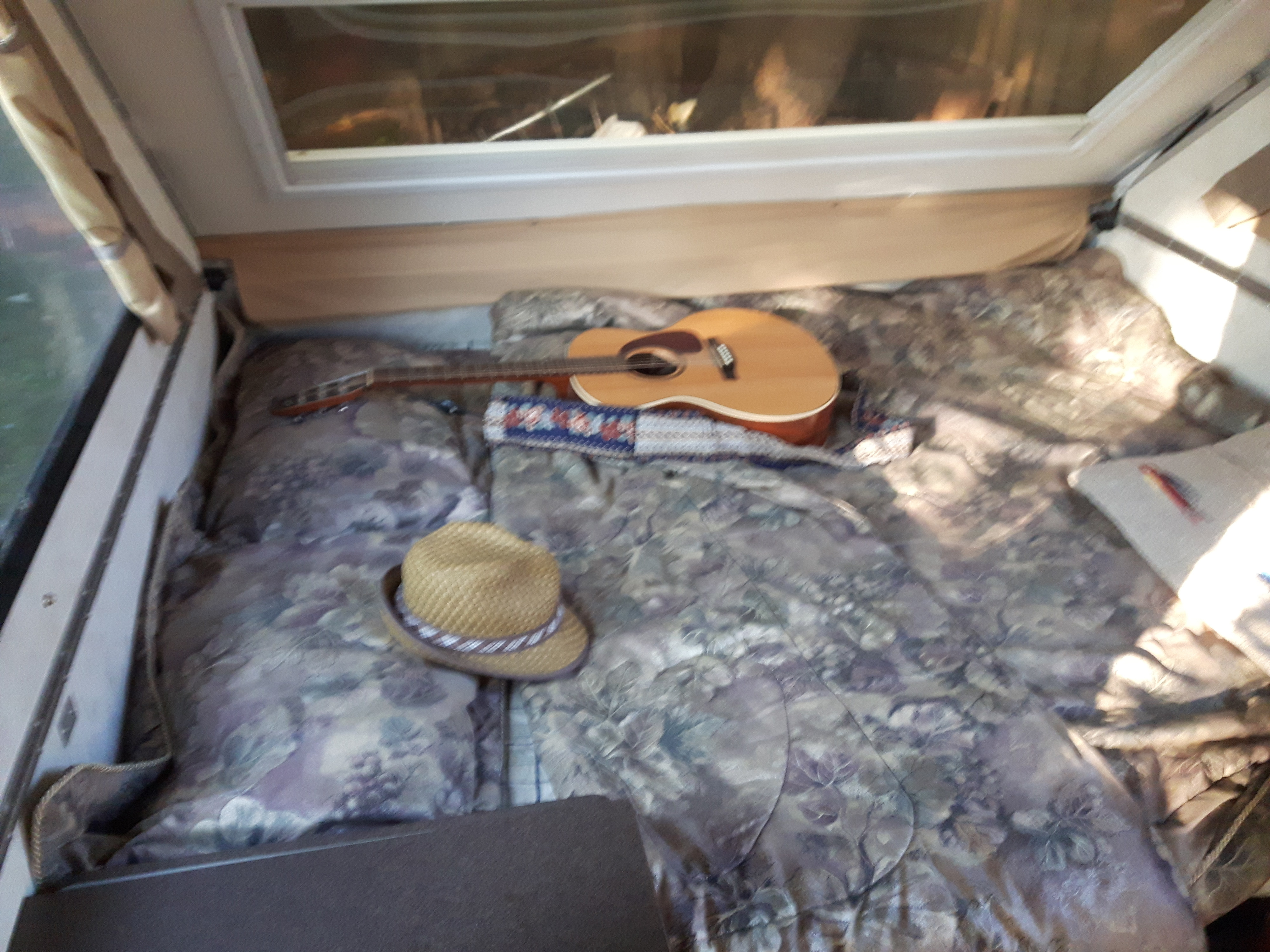 RV rental's cozy bed with floral quilt, acoustic guitar, & straw hat awaits your relaxing getaway.. A-Liner Classic 2013