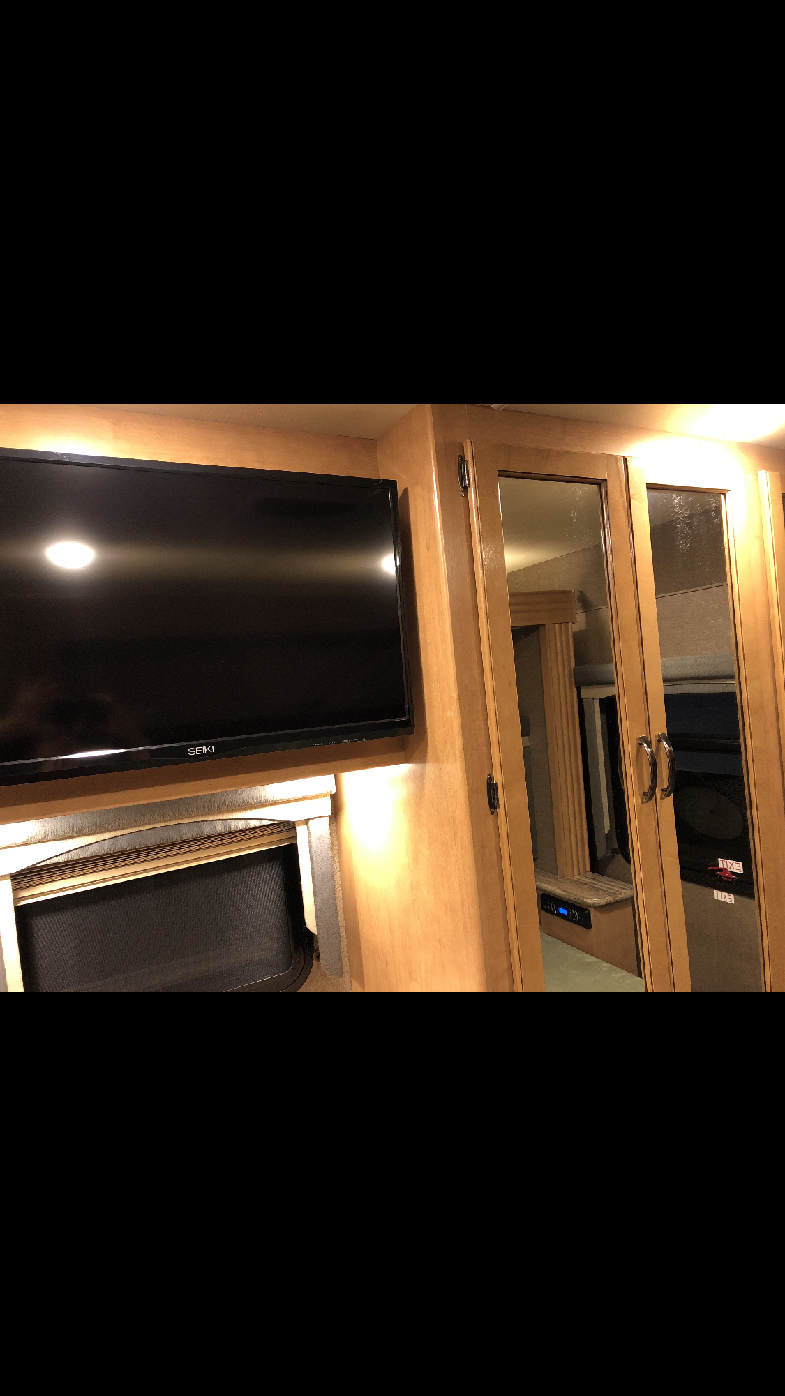 RV rental's compact interior: features a wall-mounted TV, fireplace unit, and mirrored storage cabinets.. Thor Motor Coach A.C.E 2017