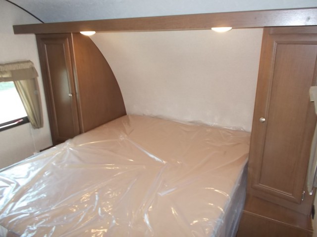 Discover this comfortable RV rental bedroom, featuring a protected bed, built-in cabinets, and bedside lights, ready for travel.. Forest River Shasta Oasis 2018