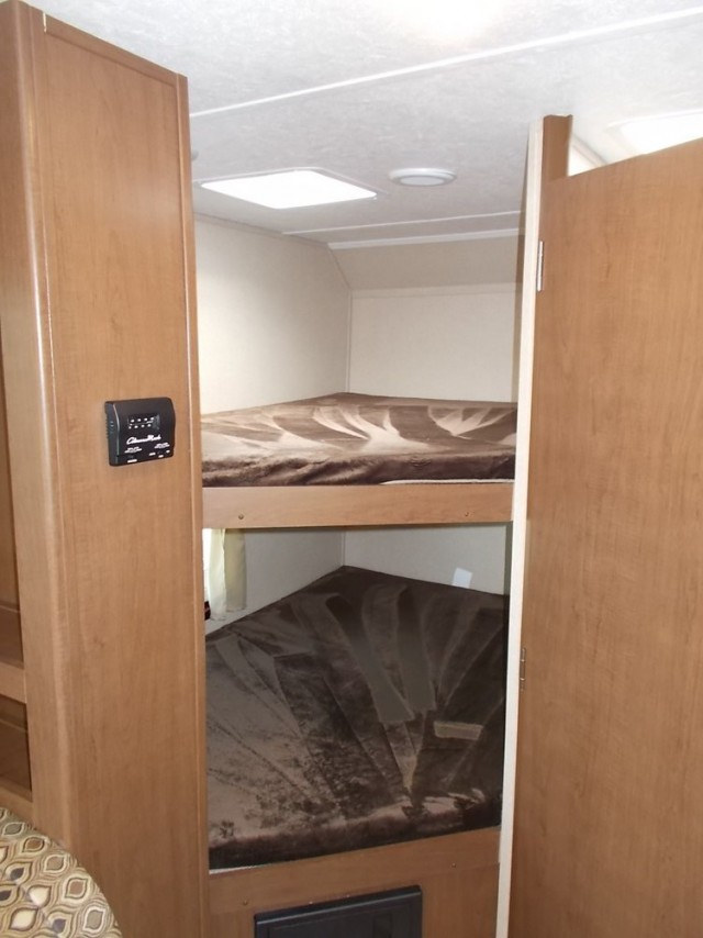 RV rental interior showcasing two built-in bunk beds with brown blankets, offering a compact sleeping area.. Forest River Shasta Oasis 2018